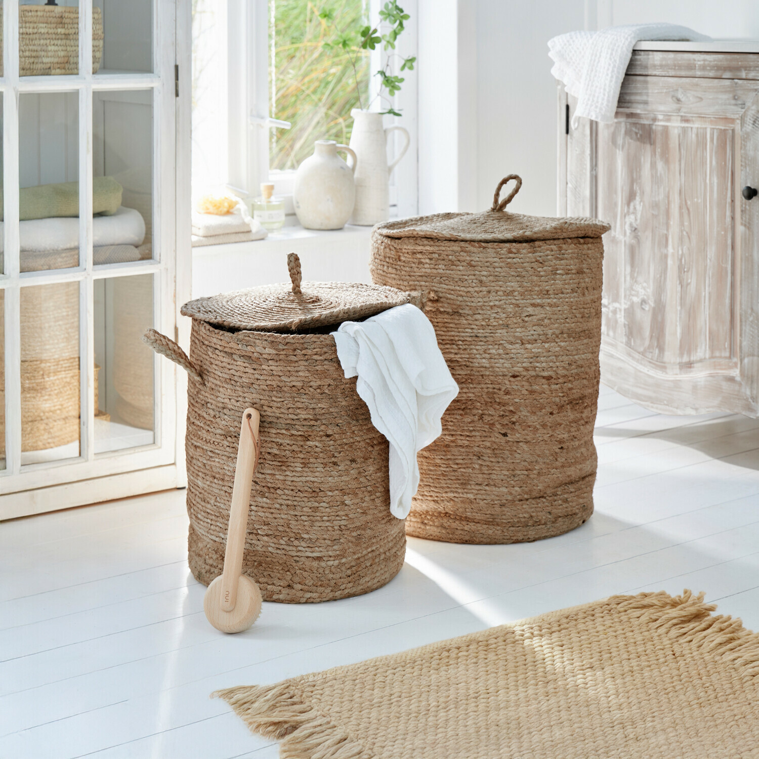 Coppia di cesti portabiancheria Kory Due ceste rotonde per biancheria in juta naturale beige in un bagno luminoso