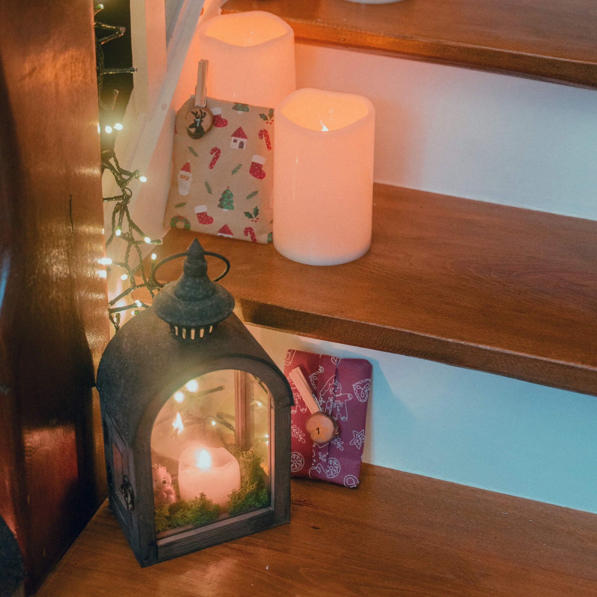 Lanterna in metallo con candela bianca e regali di Natale su scale in legno decorate