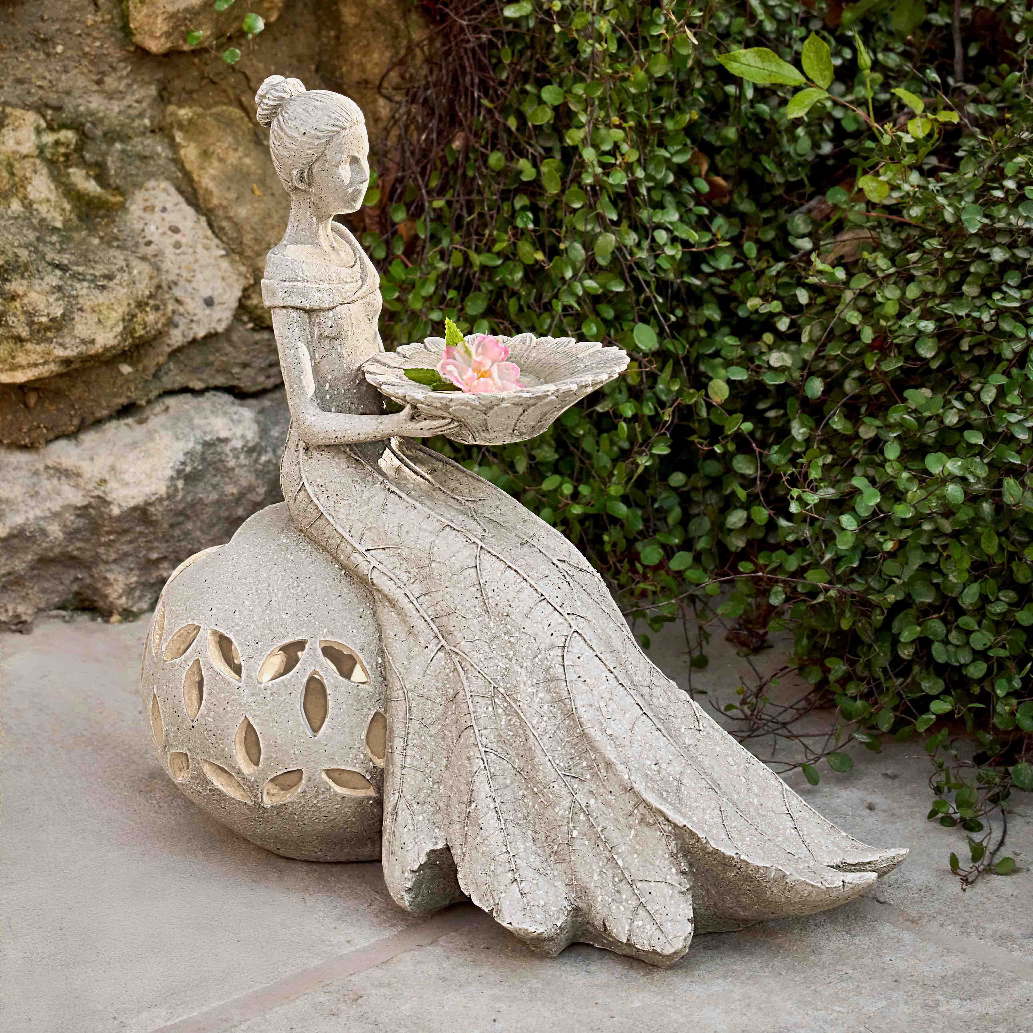 Statua da giardino in pietra raffigurante donna seduta con ciotola decorativa e fiore rosa