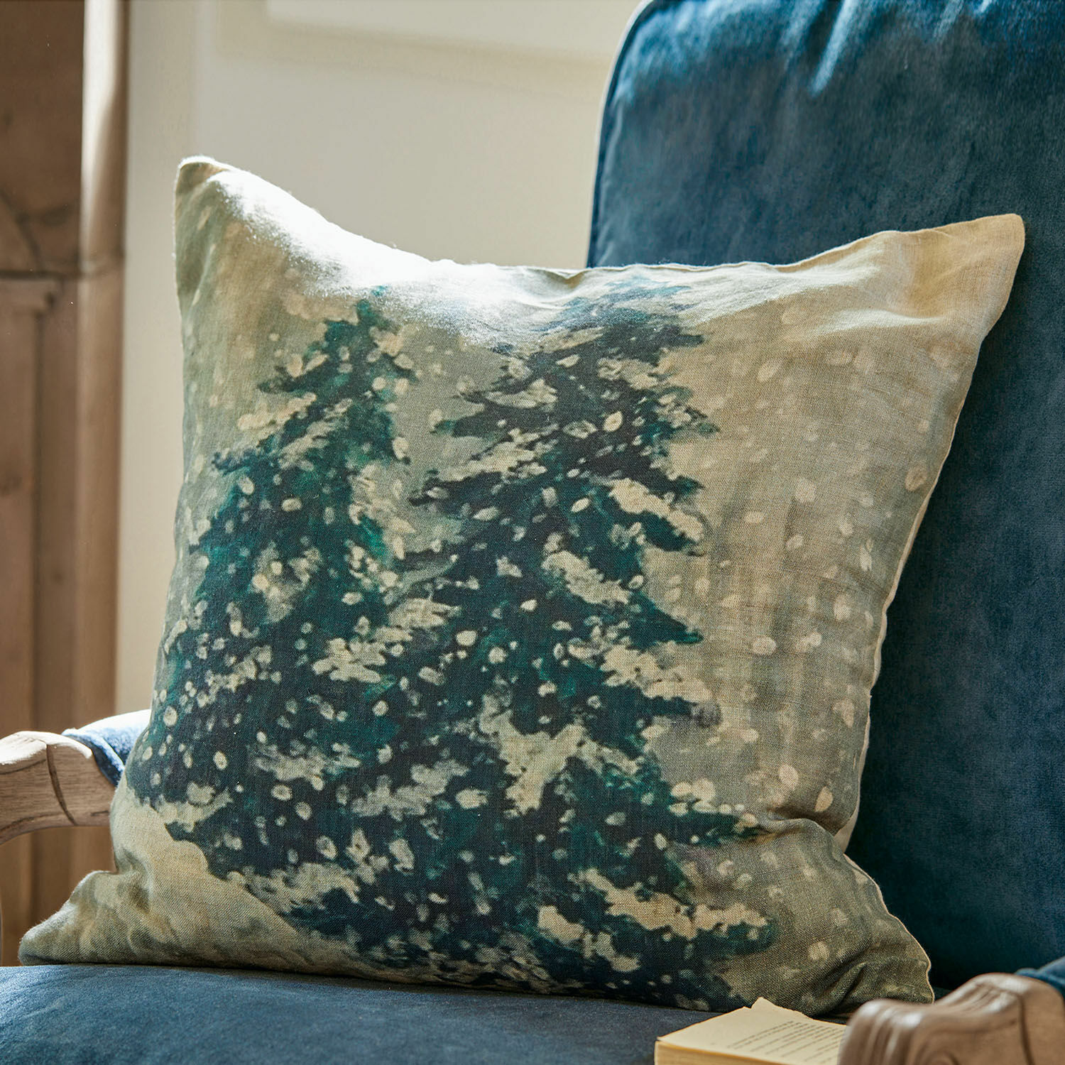 Copricuscino Mierta Cuscino decorativo in lino con stampa di alberi verdi su sfondo beige su poltrona blu