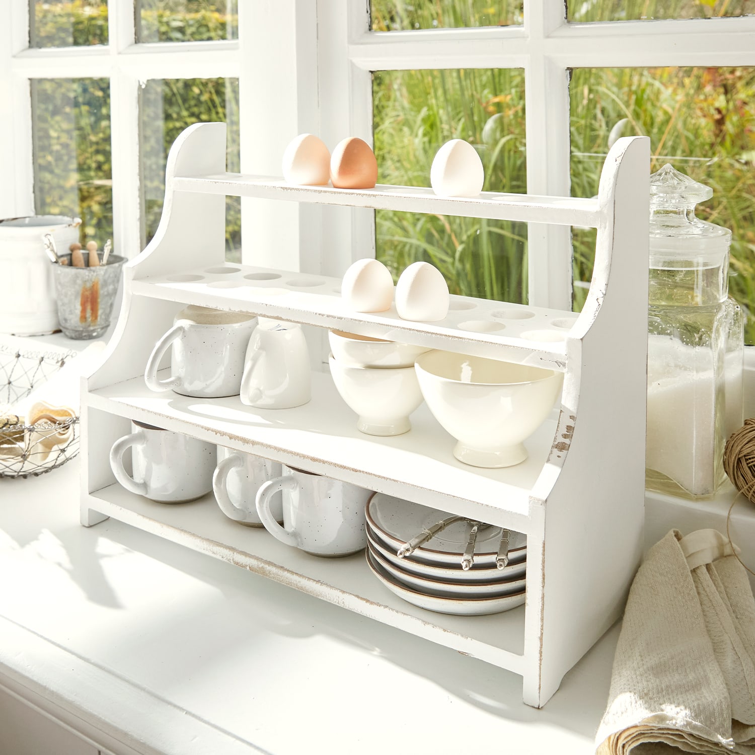 Scaffale da cucina in legno bianco con spazio per uova, tazze e ciotole in cucina luminosa