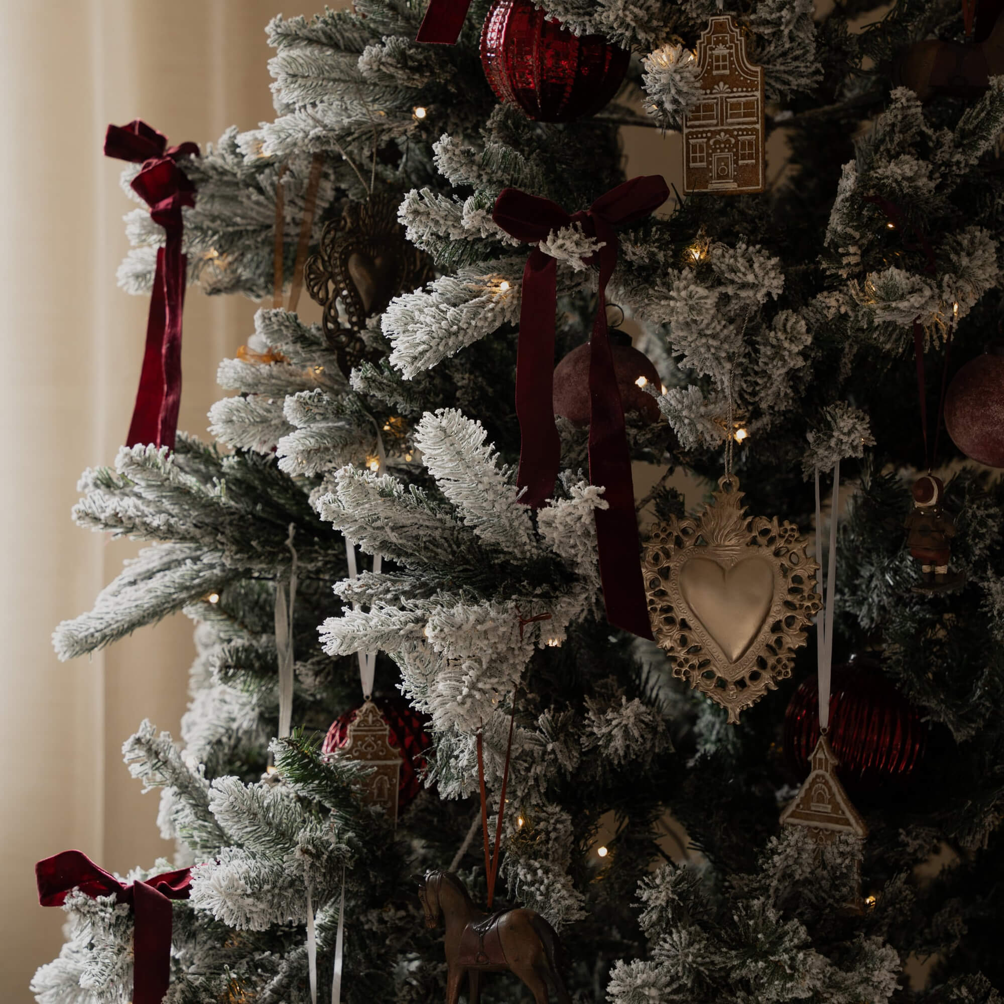 Albero di Natale artificiale con neve bianca, nastri rossi e decorazioni tradizionali