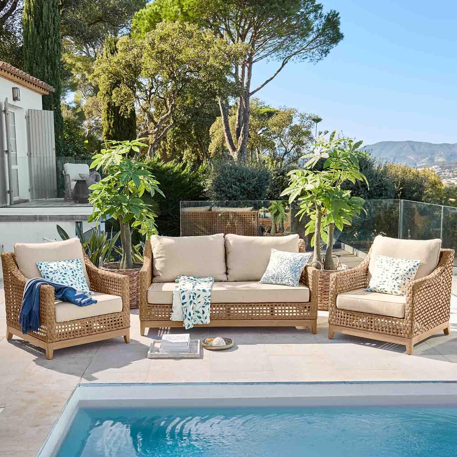 Set di mobili da giardino in rattan naturale con cuscini beige accanto alla piscina
