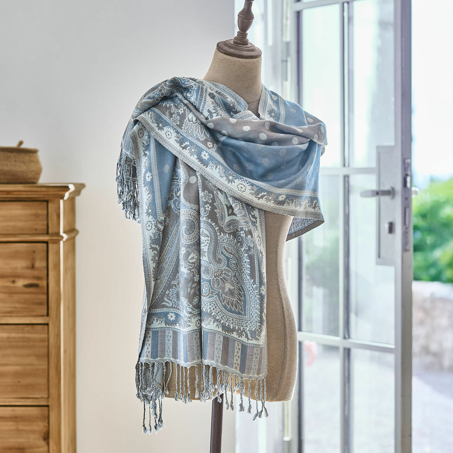 Sciarpa Bijapur Sciarpa blu-grigia con motivo paisley e frange su manichino in ambiente luminoso