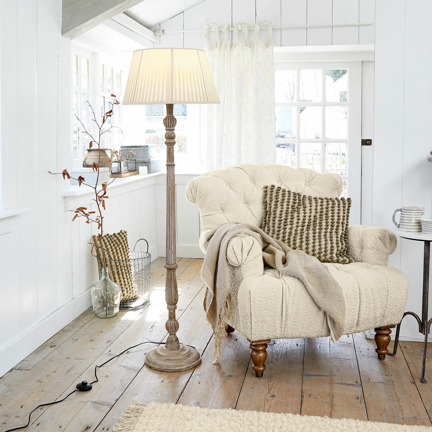 Lampada a stelo Morten Poltrona beige in tessuto bouclé con cuscino e lampada da terra in soggiorno luminoso in legno