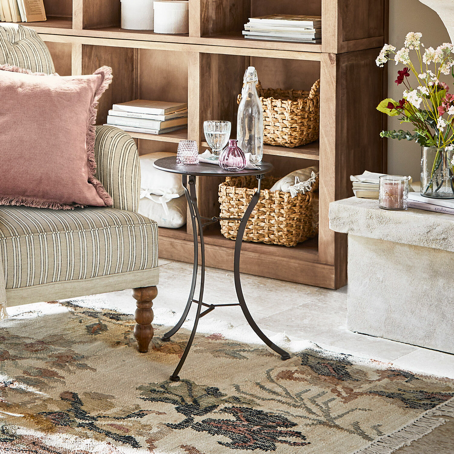 Tavolino di complemento Torrance Tavolino laterale in metallo nero davanti a scaffale in legno e poltrona beige con cuscino rosa