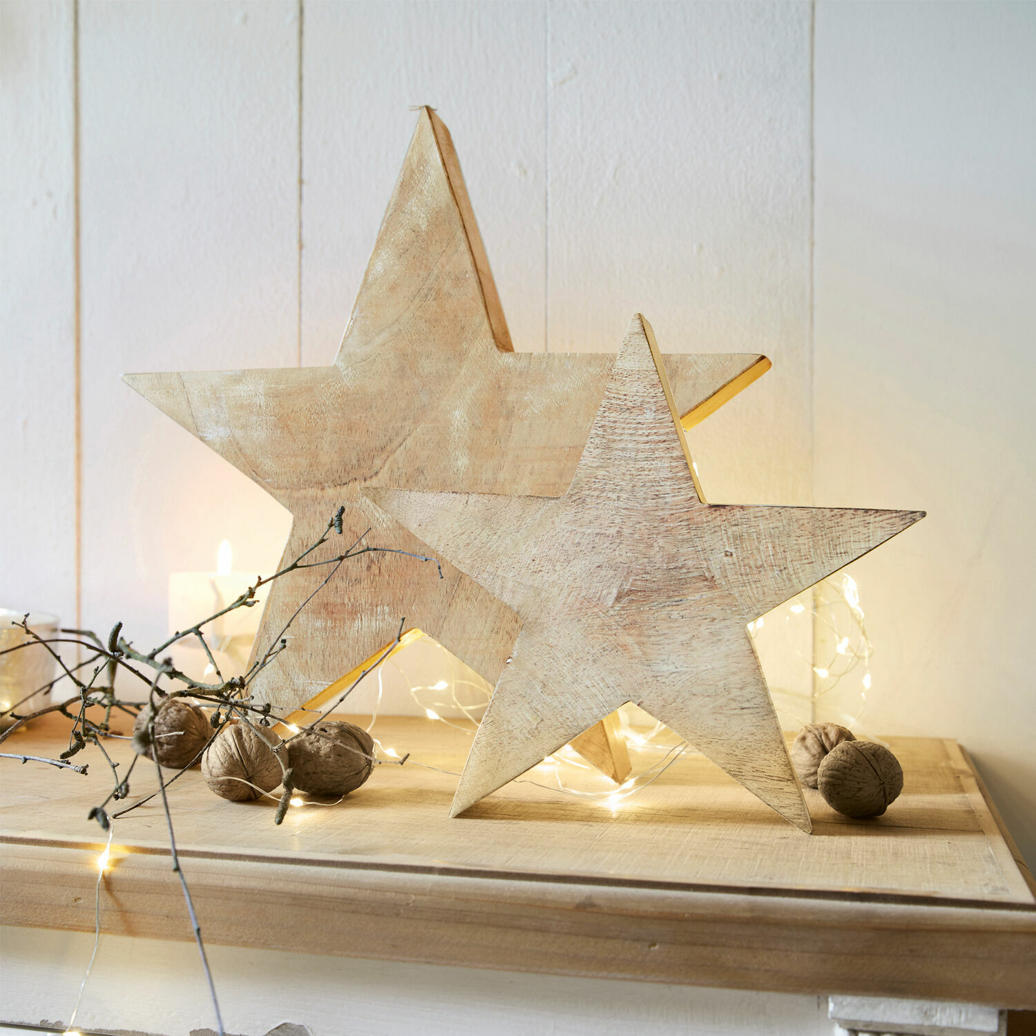 Coppia di stelle Dunino Decorazioni in legno a forma di stella colore naturale su tavolo festivo con noci e luci LED