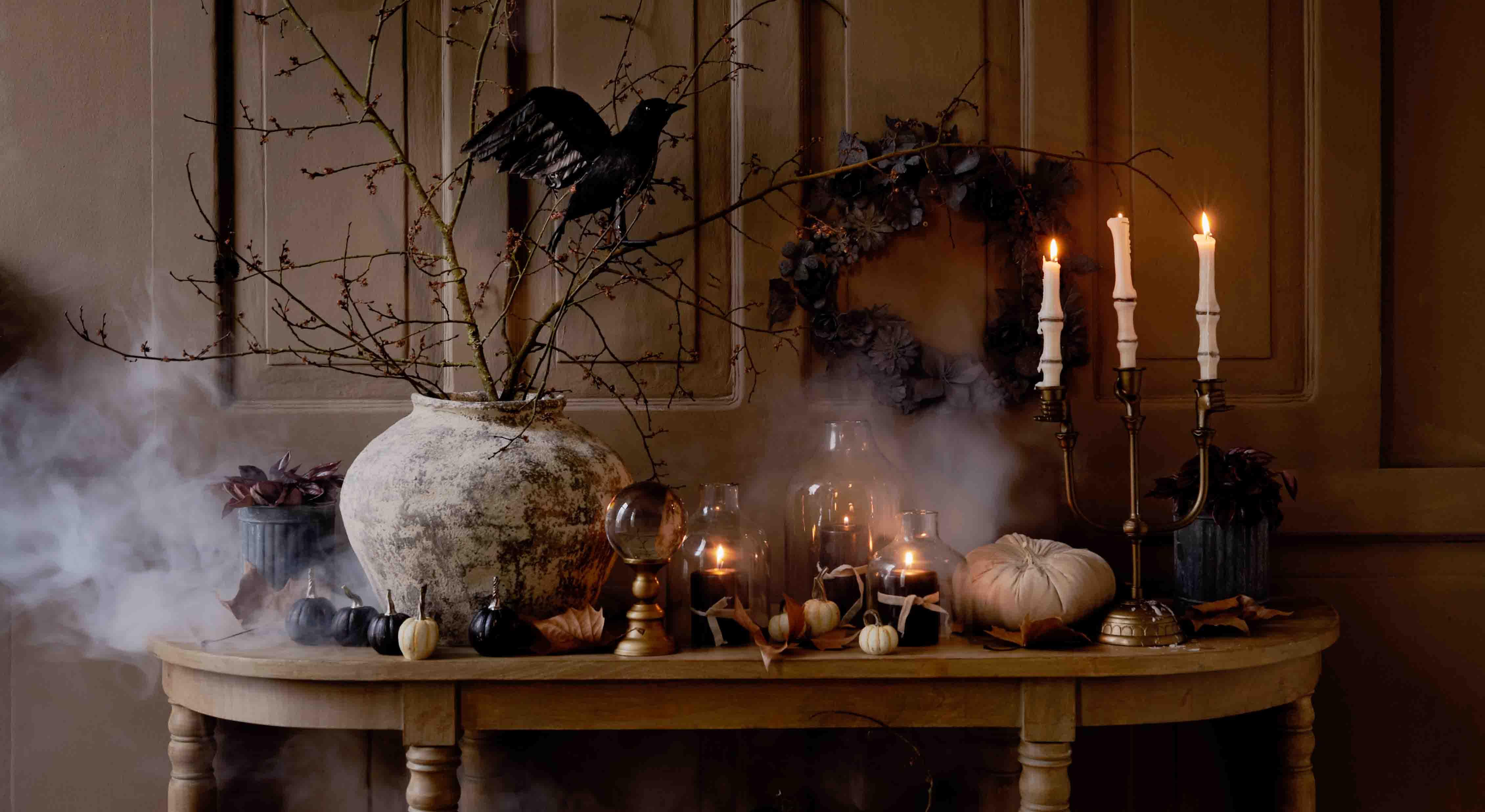 Tavolo rustico con decorazioni autunnali di zucche, candele e rami in vaso di ceramica, illuminazione d'atmosfera