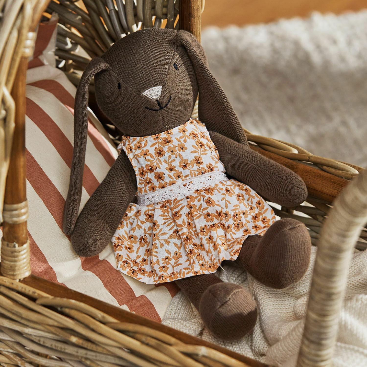 Peluche Pippaloo Coniglio di peluche marrone con vestito a fiori su poltrona in vimini con cuscino a righe