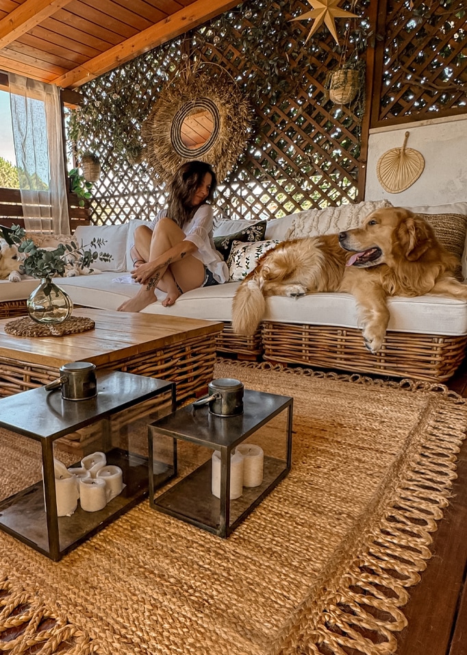 Soggiorno accogliente con divano in rattan, tappeto naturale e decorazioni in erba marina in tonalità beige calde.