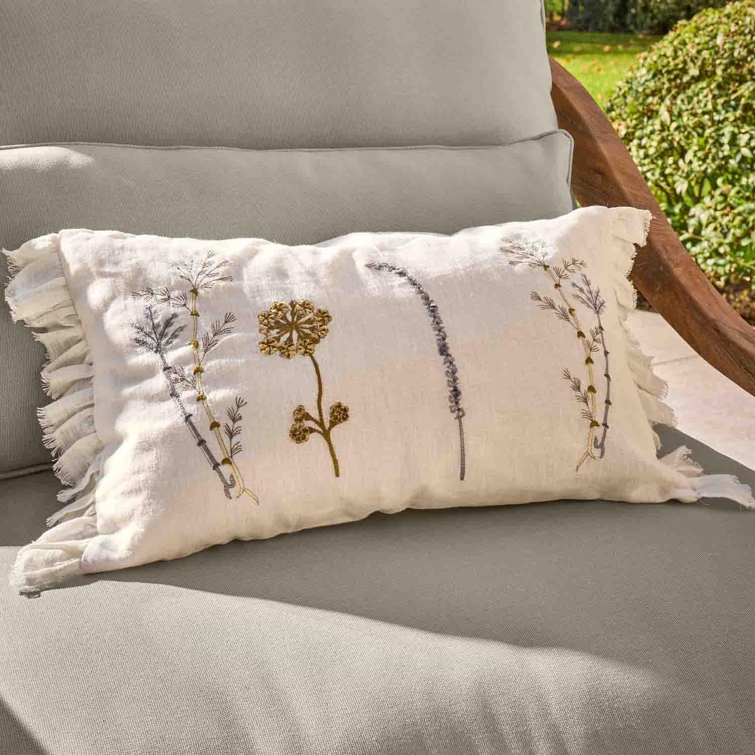 Cuscino rettangolare in lino bianco con ricamo floreale e volant su poltrona da giardino grigia