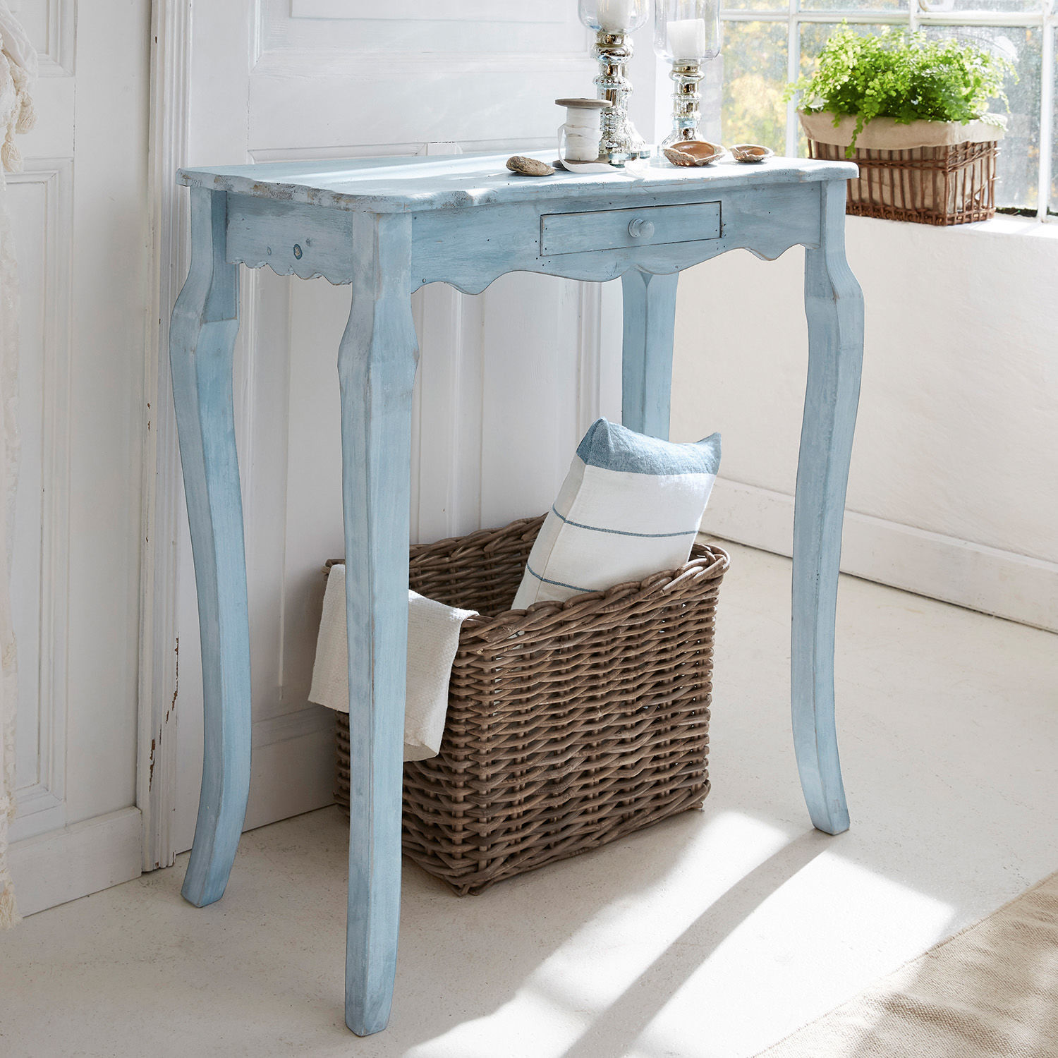 Consolle Barbey Tavolino in legno blu stile vintage con cassetto e cesta di vimini, decorato vicino a finestra luminosa