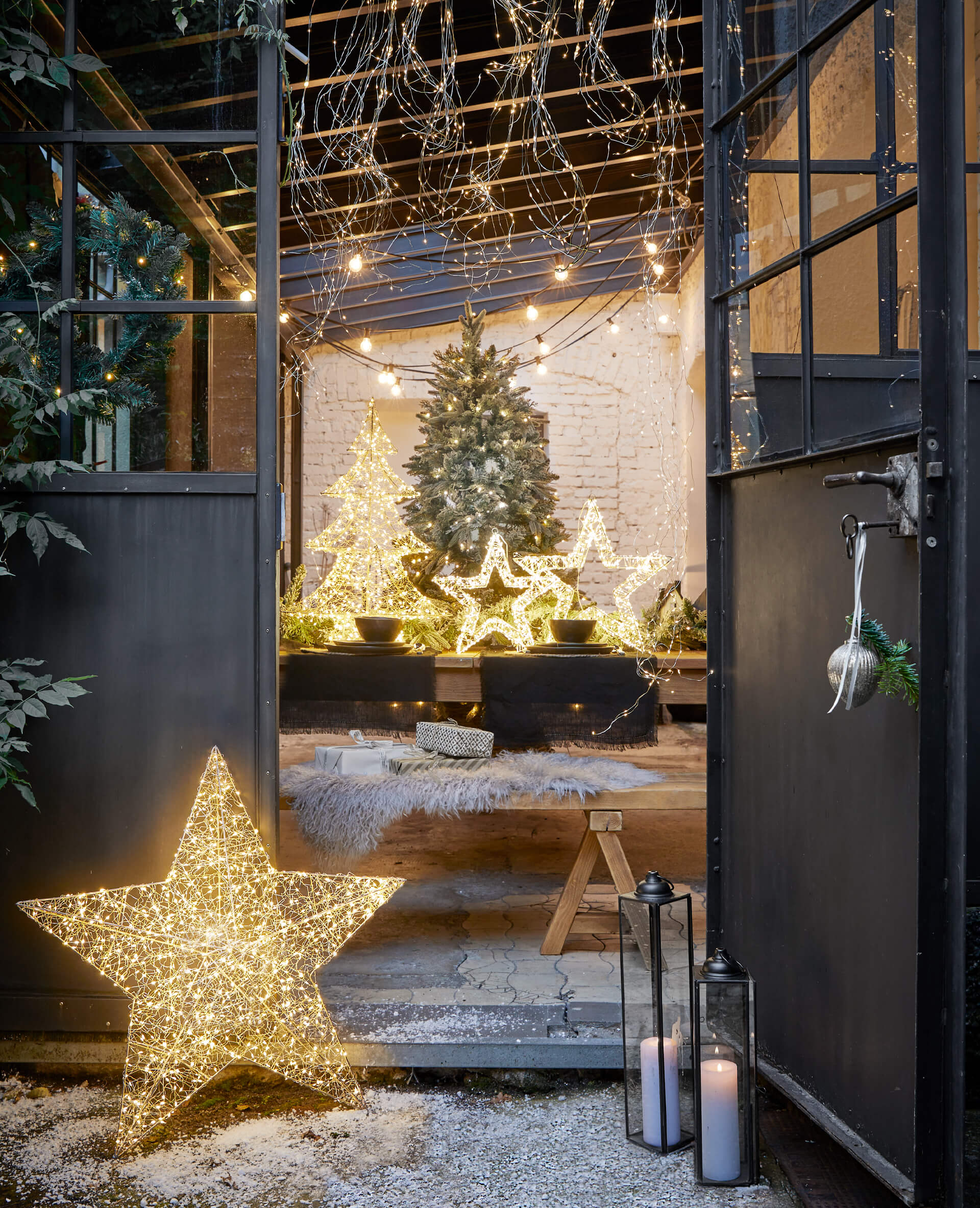 Decorazioni natalizie LED a forma di stelle e alberi con luce calda davanti a porte nere aperte
