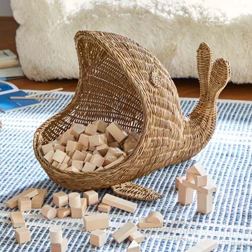 Cesto in vimini a forma di lumaca con blocchi di legno su tappeto blu