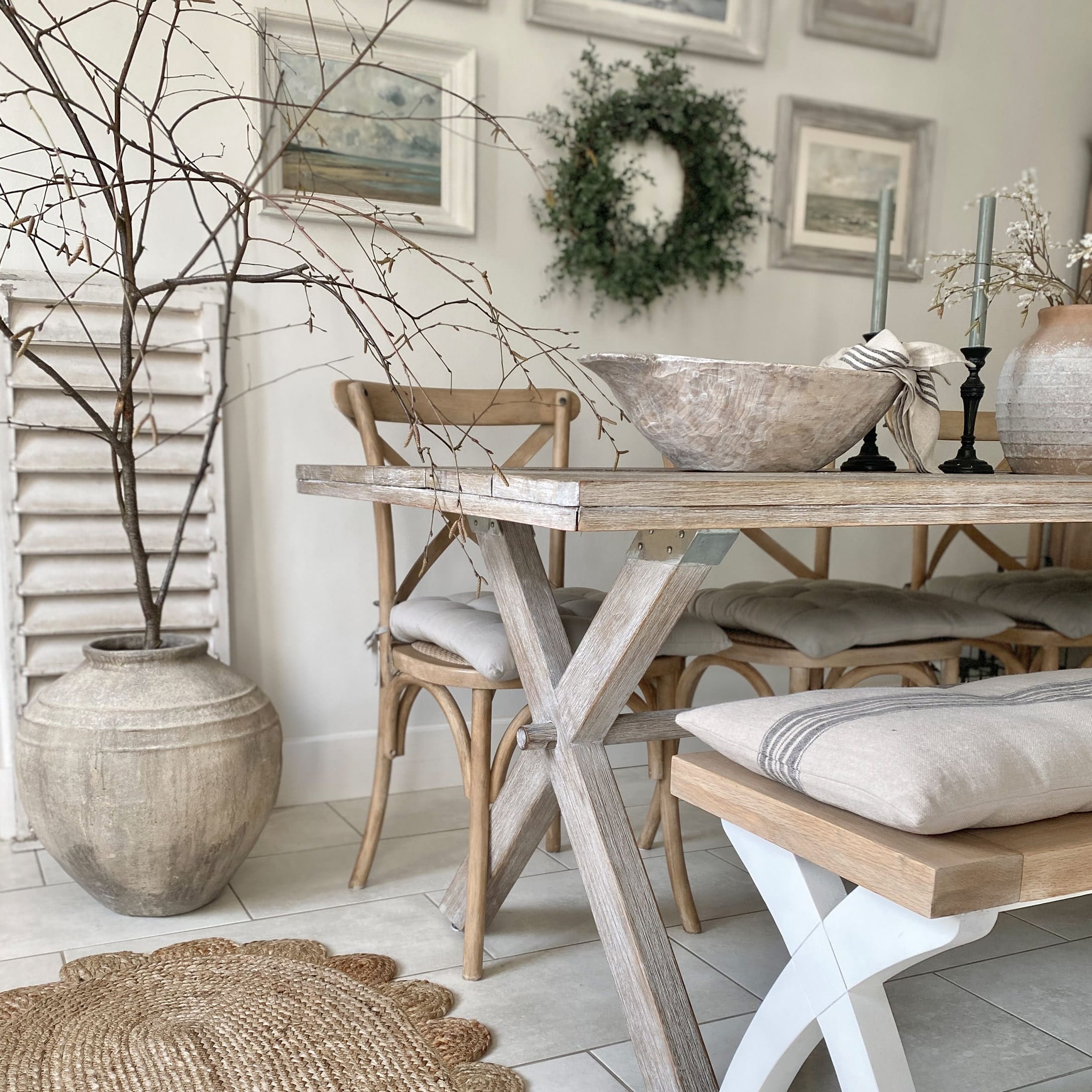 Sala da pranzo con tavolo in legno chiaro, sedie abbinate, decorazioni naturali e cuscini