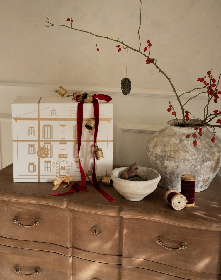 Decorazione natalizia con scatola bianca, nastri rossi e vaso in ceramica con ramo e bacche rosse