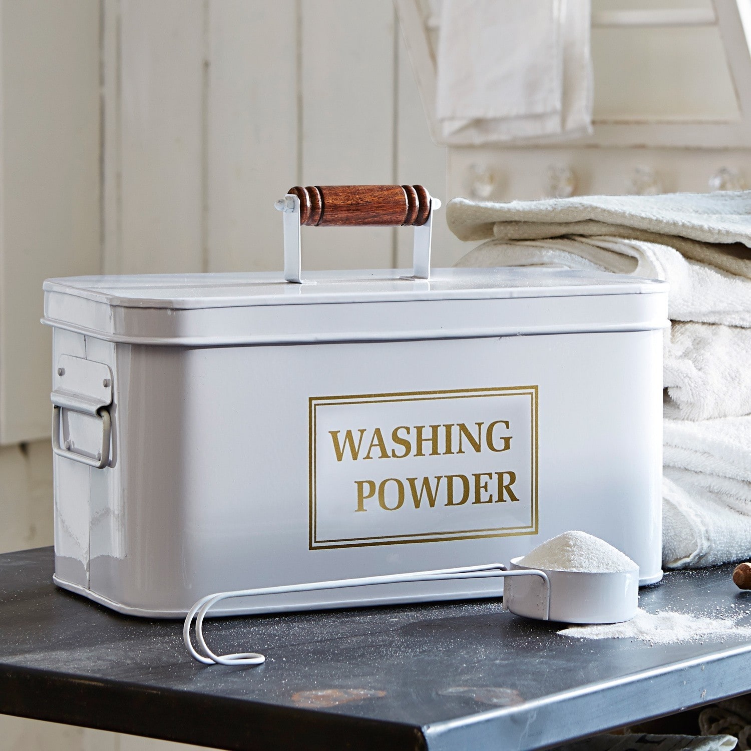 Contenitore per detersivo Washing Contenitore metallico bianco per detersivo in polvere con manico in legno e misurino su tavolo nero