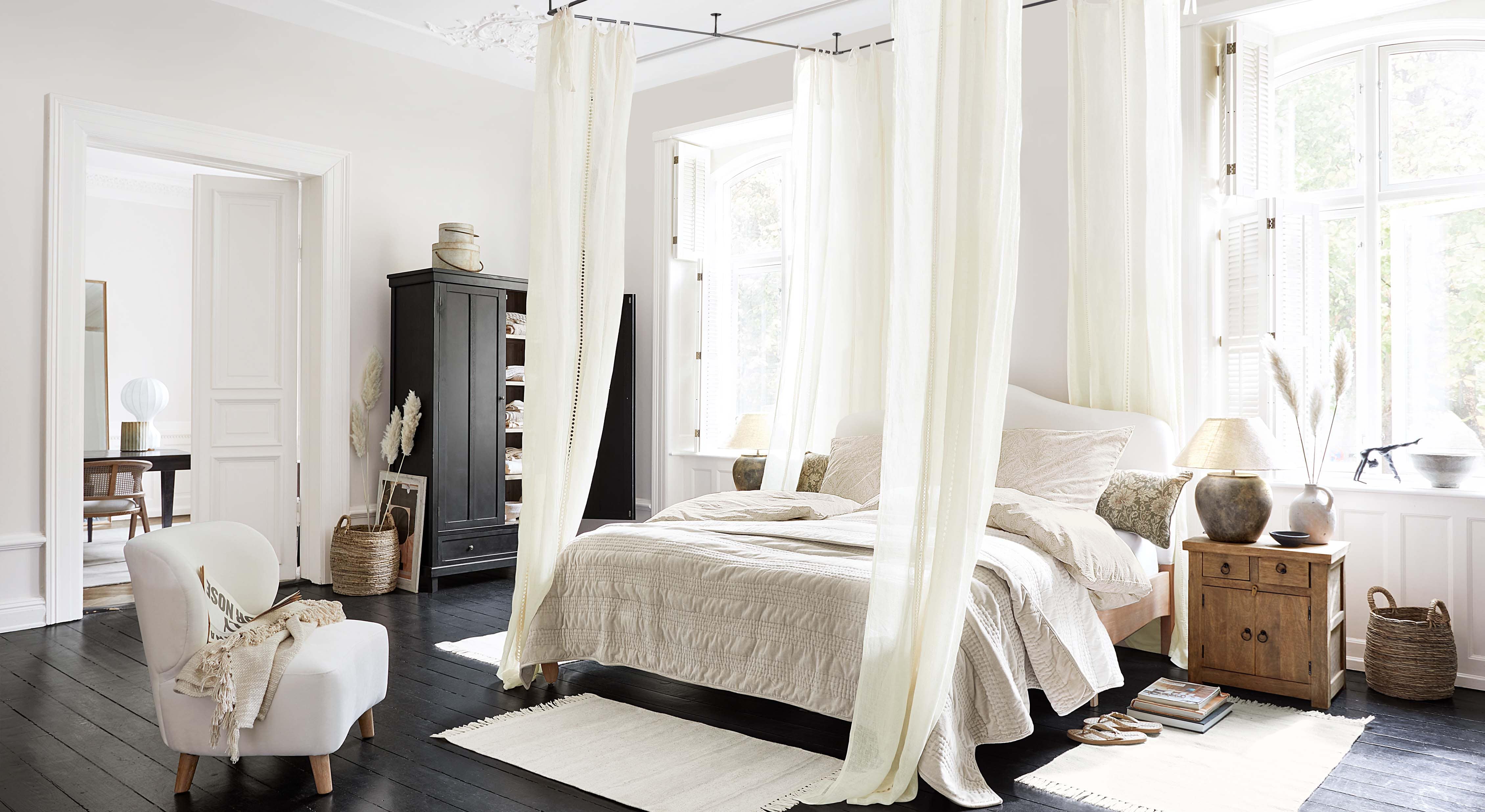 Camera da letto accogliente con letto a baldacchino, biancheria beige chiaro e mobili in legno stile scandinavo
