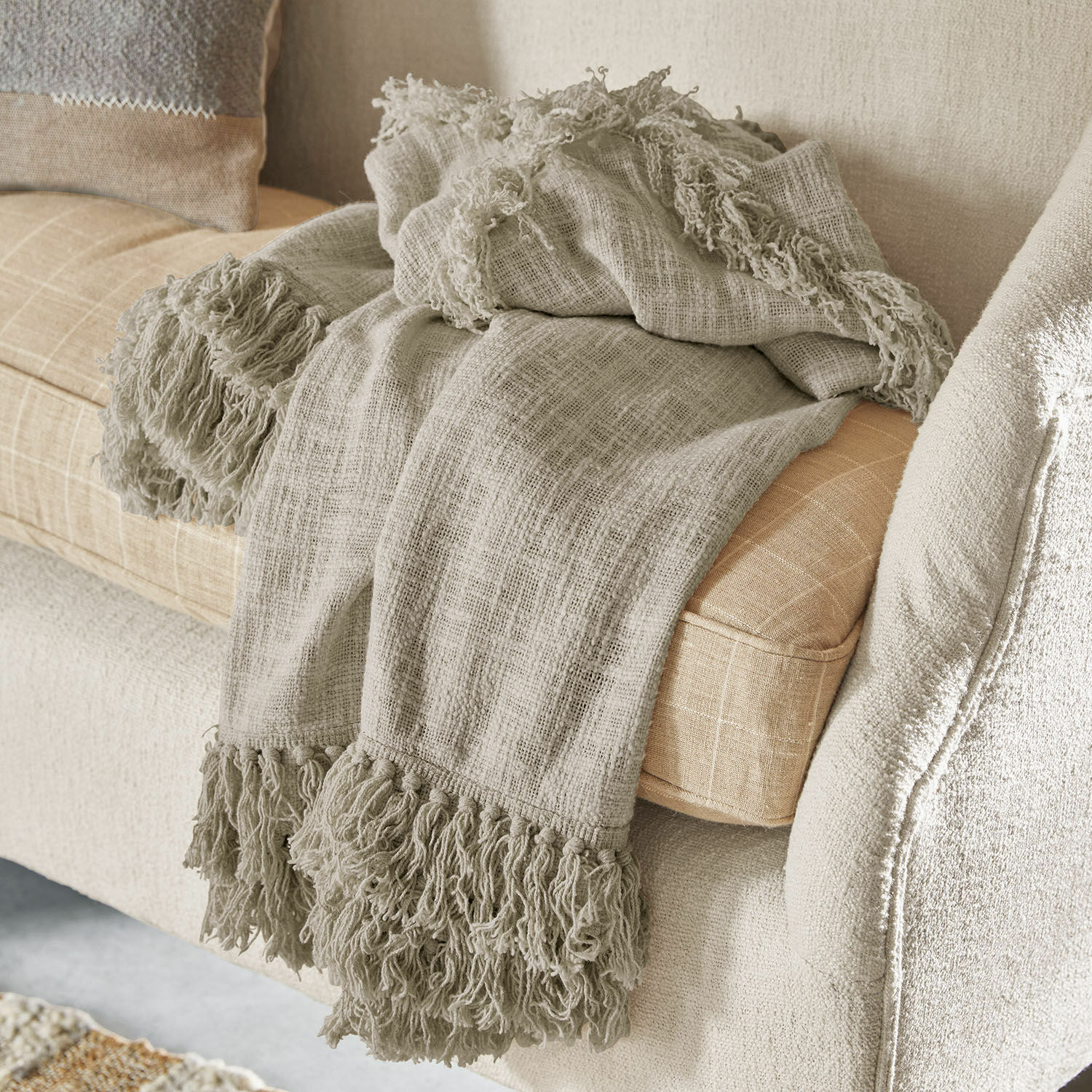 Plaid Freya Plaid beige con frange in tessuto morbido su divano chiaro, decorazione accogliente