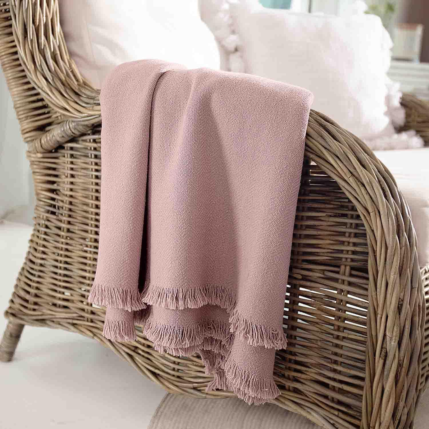 Coperta rosa in tessuto morbido con frange su poltrona in vimini, decorazione e comfort casa