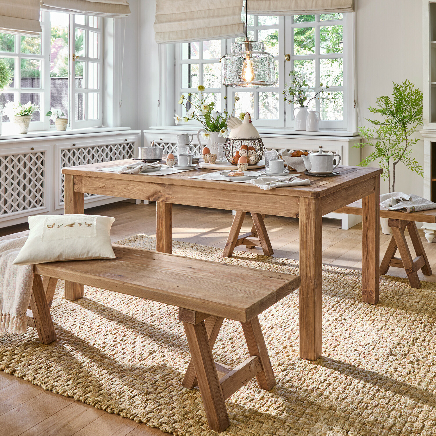 Tavolo Amherst Sala da pranzo con tavolo e panche in legno su tappeto naturale, interno luminoso con decorazioni e luce