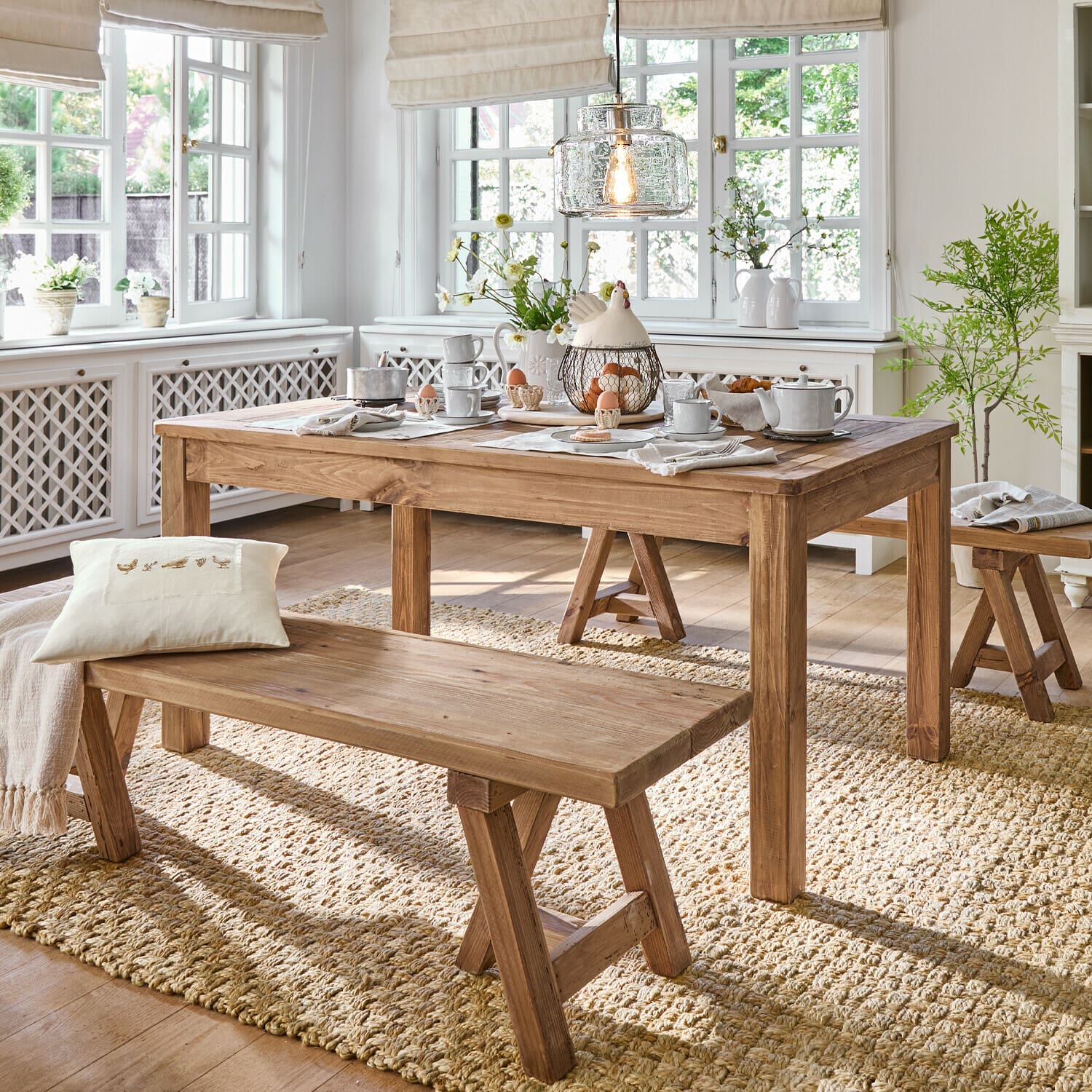Tavolo Amherst Sala da pranzo con tavolo e panche in legno su tappeto naturale, interno luminoso con decorazioni e luce