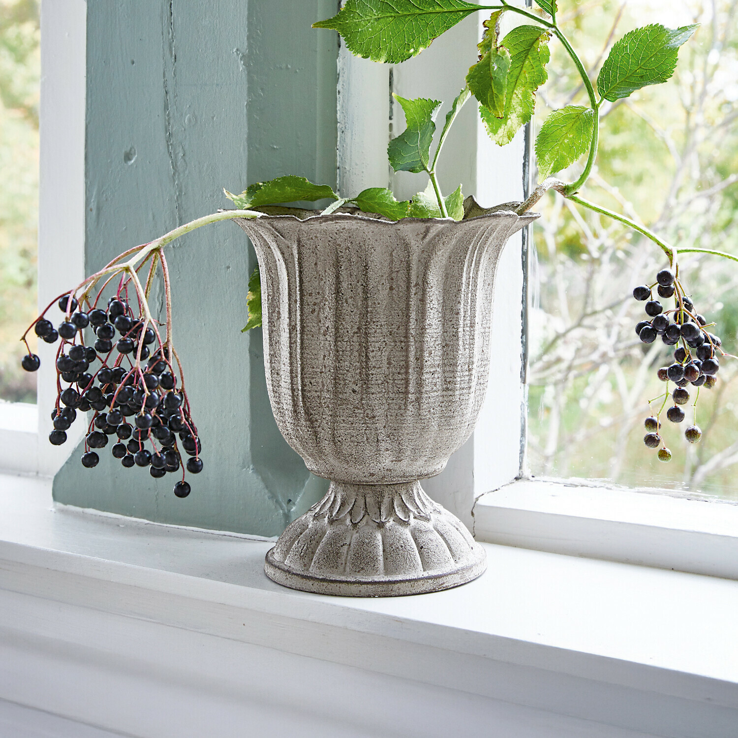 Vaso Hanson Vaso in ceramica grigia con pianta e bacche sul davanzale, decorazione naturale