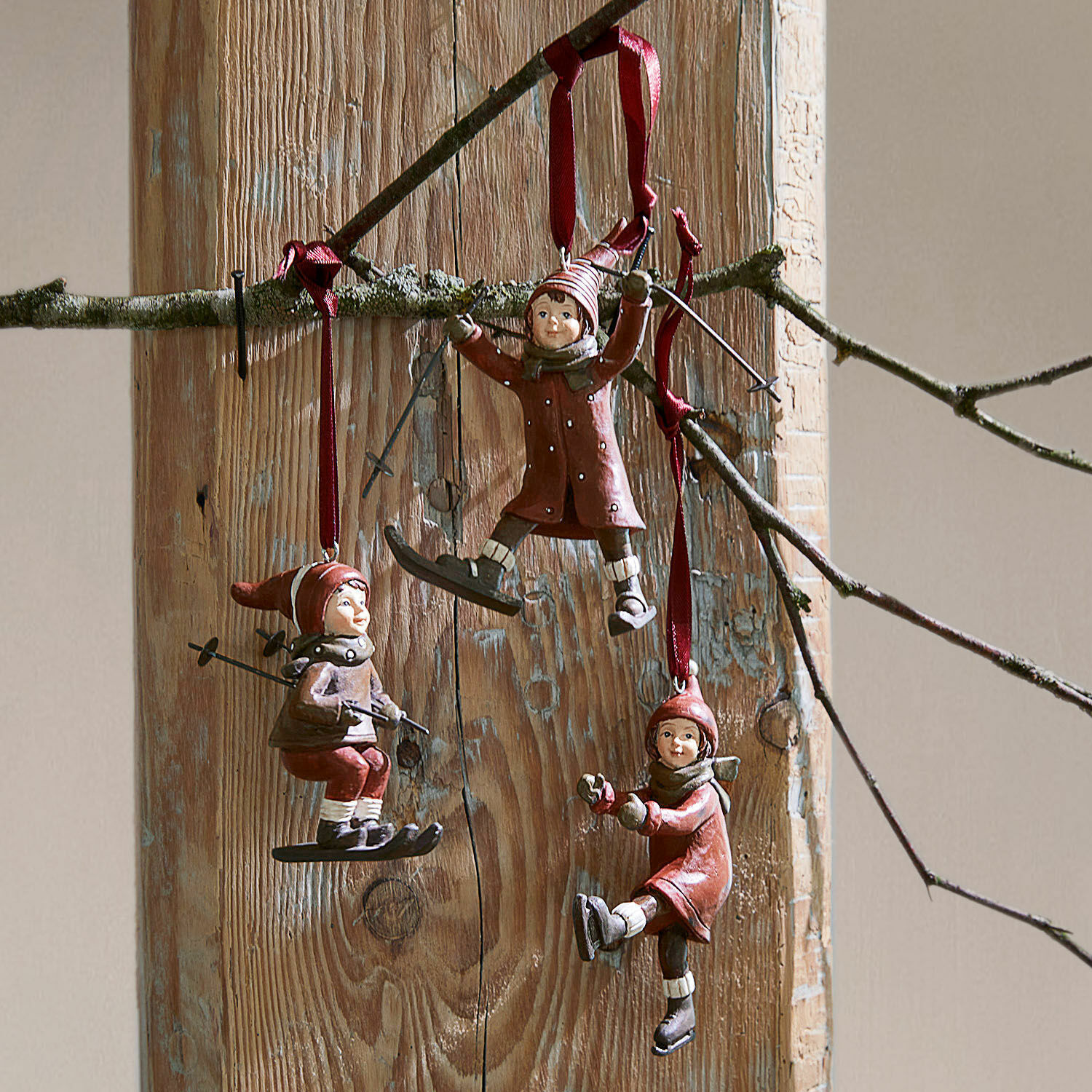 Set di 3 decorazioni da appendere Bibury Tre decorazioni rosse con bambini sugli sci e sul pattinaggio appese su sfondo in legno, decorazione invernale