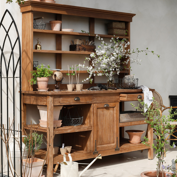 Mobile da giardino in legno con scaffali, vasi e rami fioriti, decorato con attrezzi da giardino