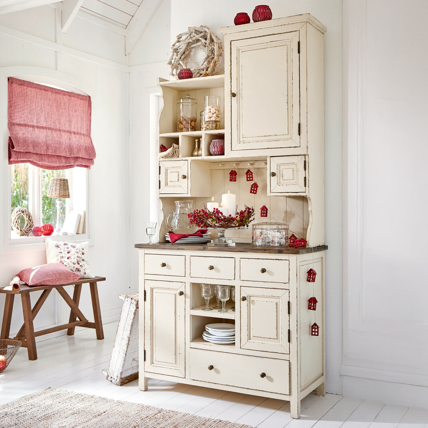 Credenza in legno crema con decorazioni natalizie rosse in stanza luminosa in stile rustico