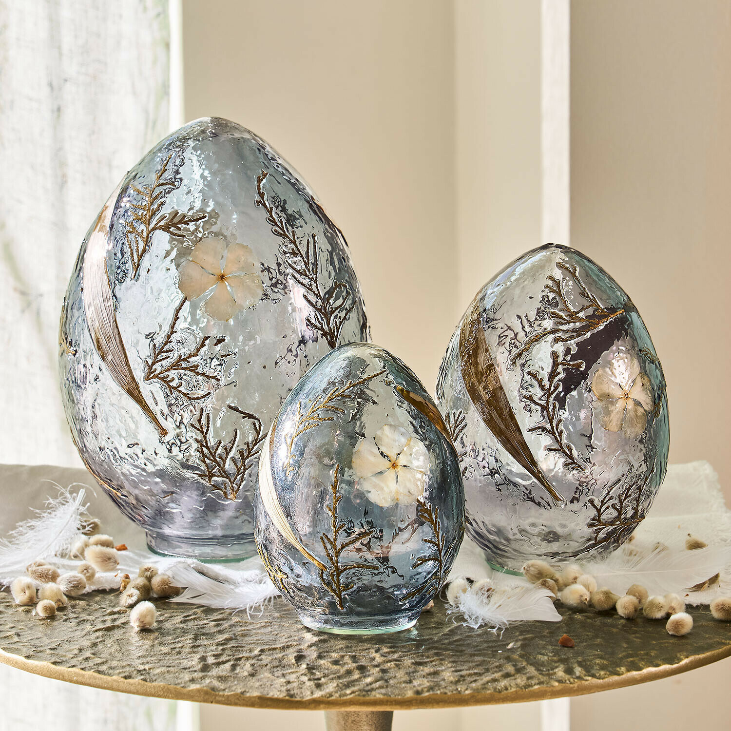 Set di 3 uova decorative Lunavelle Set di tre uova decorative in vetro grigio con fiori e foglie incastonati su tavolo
