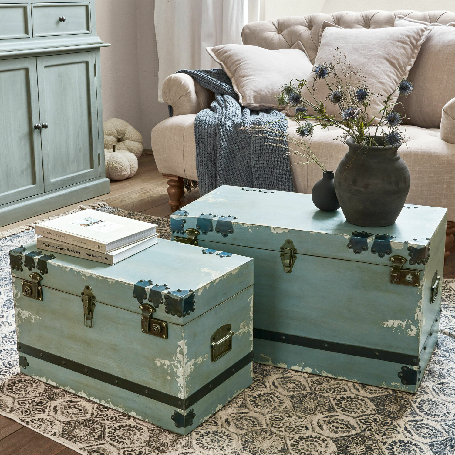 Coppia di bauli Gorman Due bauli in legno blu con ferrature metalliche su tappeto in soggiorno con divano beige