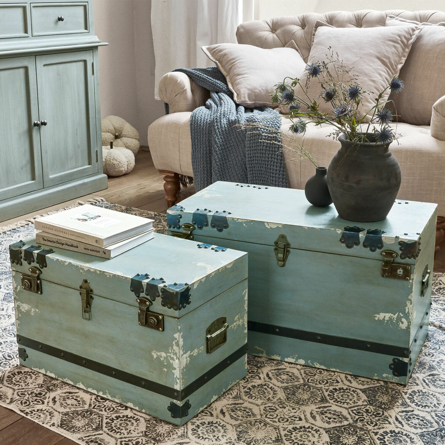 Coppia di bauli Gorman Due bauli in legno blu con ferrature metalliche su tappeto in soggiorno con divano beige