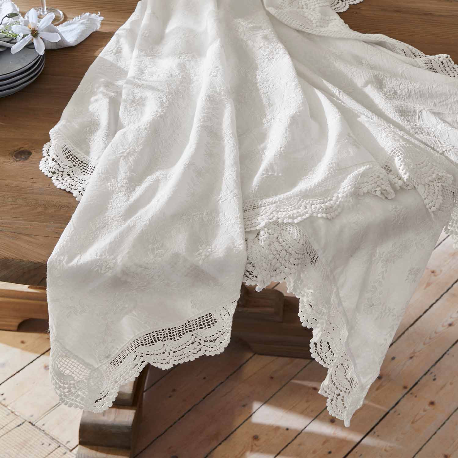 Tovaglia bianca ricamata con bordo in pizzo su tavolo in legno, decorazione elegante per tavola