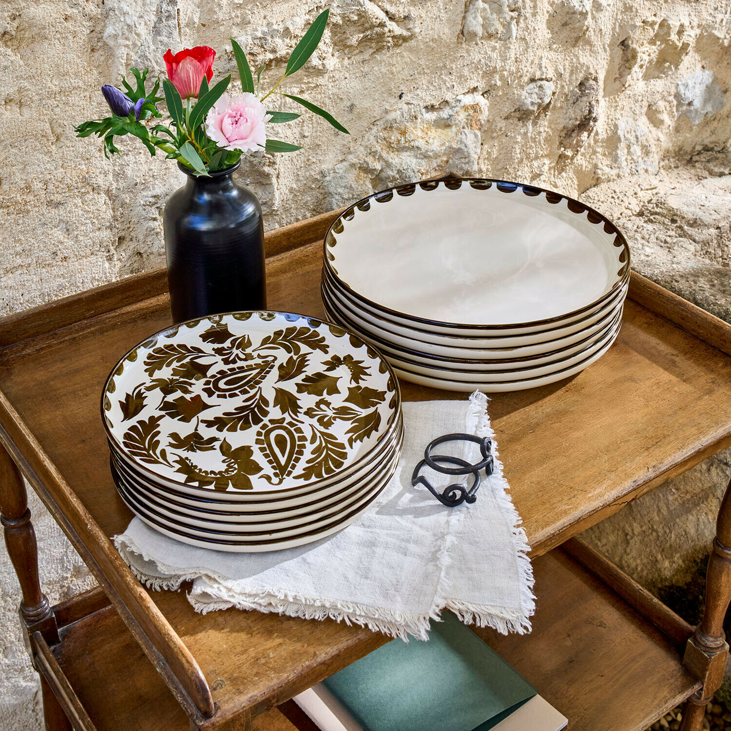 Set di 12 piatti Tazira Set di piatti in ceramica crema con motivo marrone su tavolo in legno con vaso nero e fiori