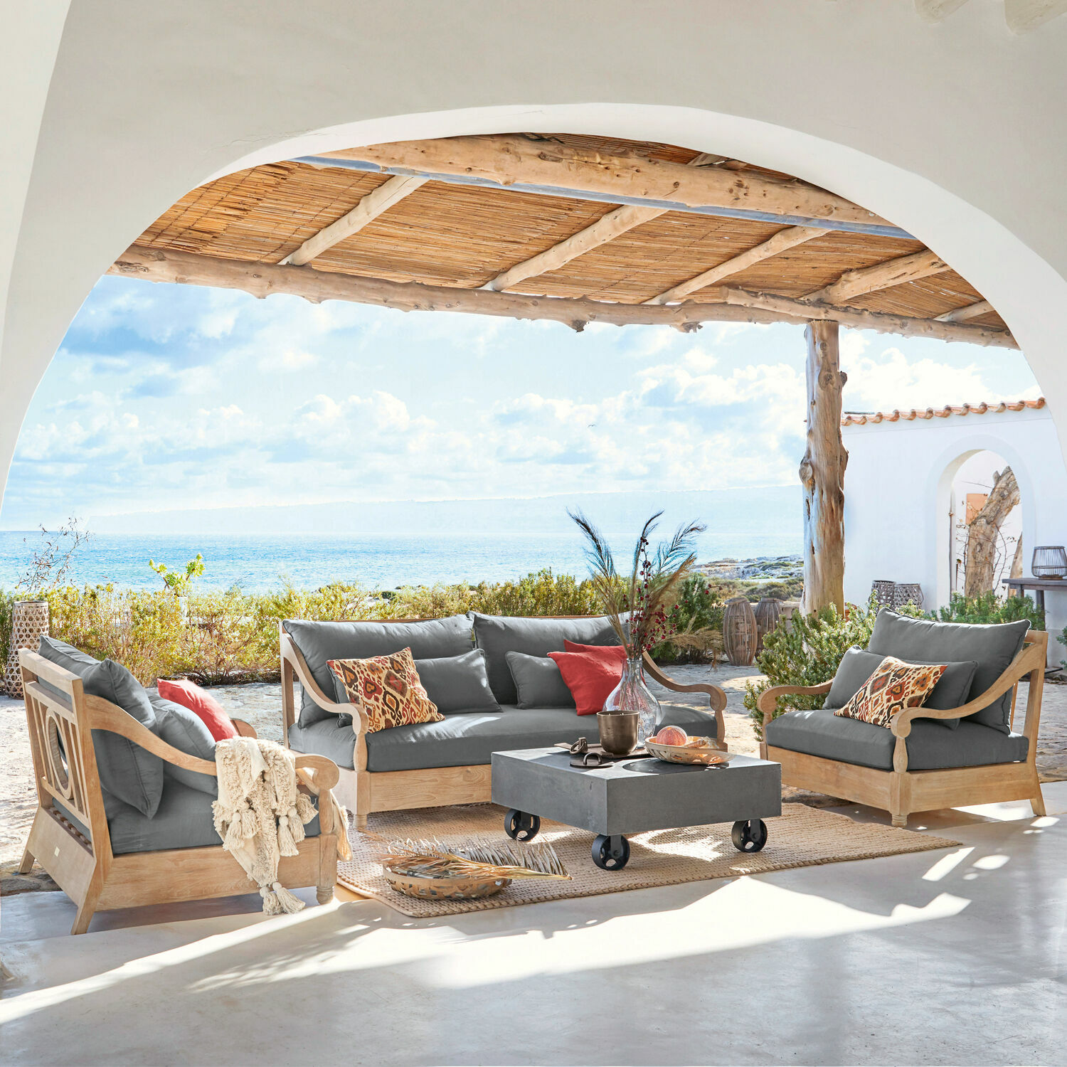 Salottino Montcassin Set di mobili da giardino in legno con cuscini grigi su terrazza con vista mare