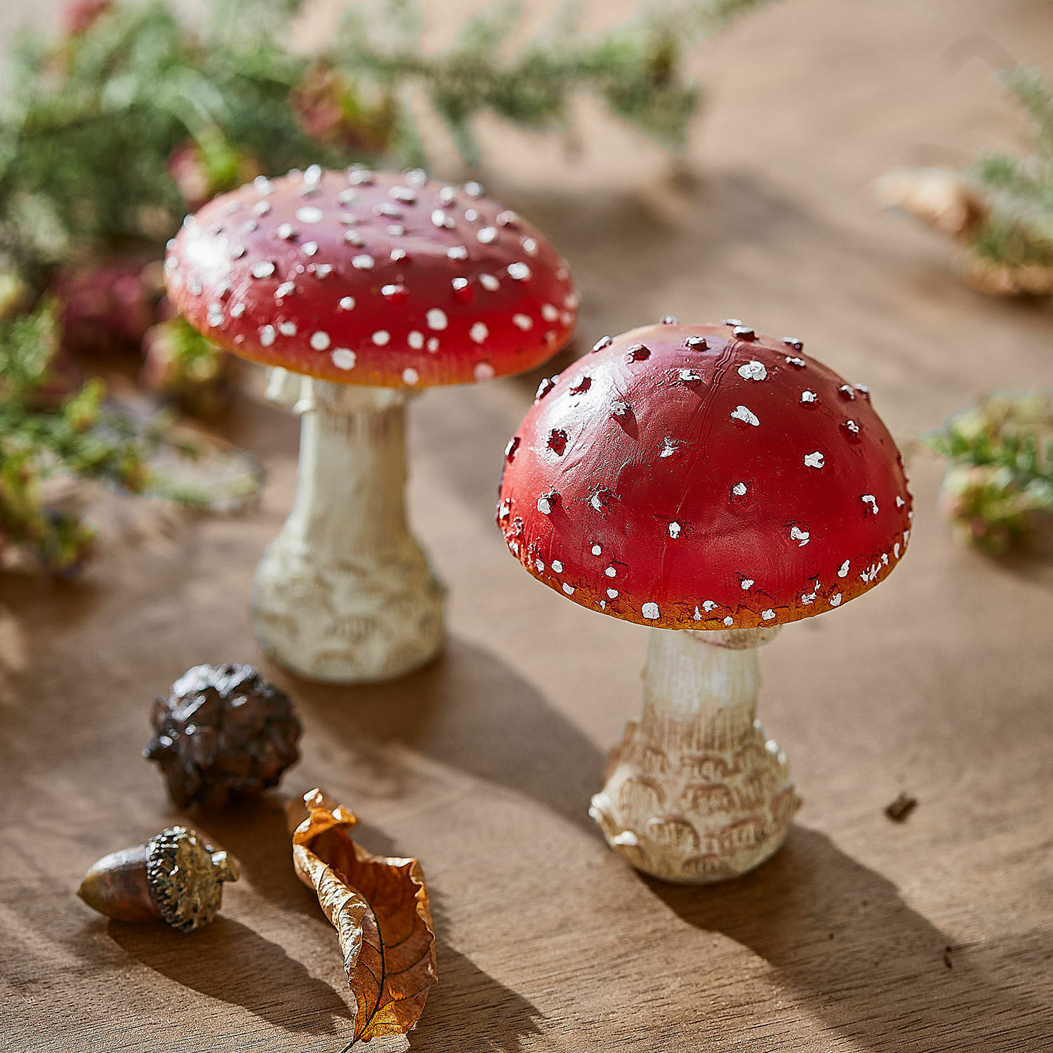 Coppia di funghi decorativi Quintelle Funghi decorativi rossi con puntini bianchi su tavolo di legno con foglia e ghianda
