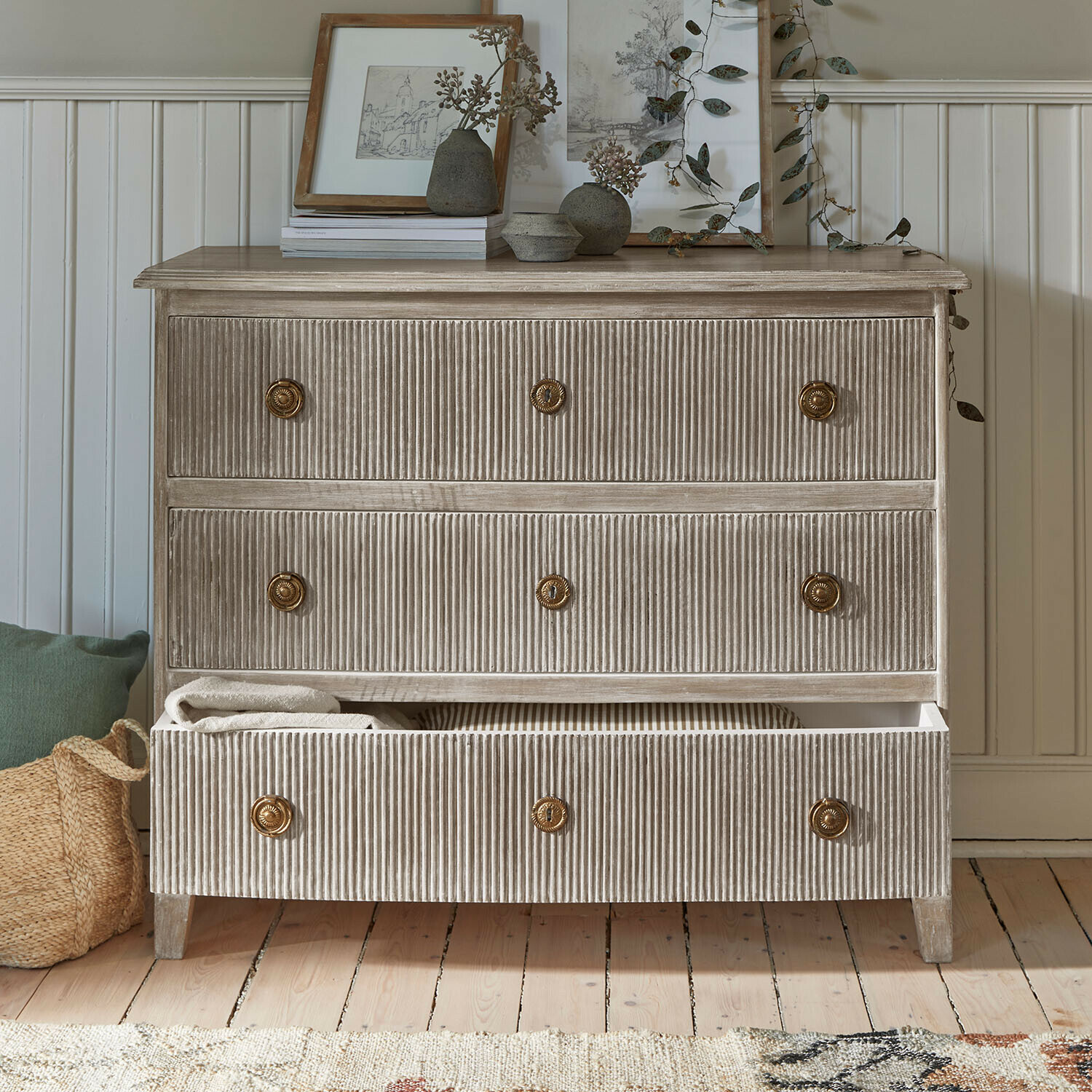 Comò in legno scanalato beige con maniglie in ottone e decorazioni sulla superficie