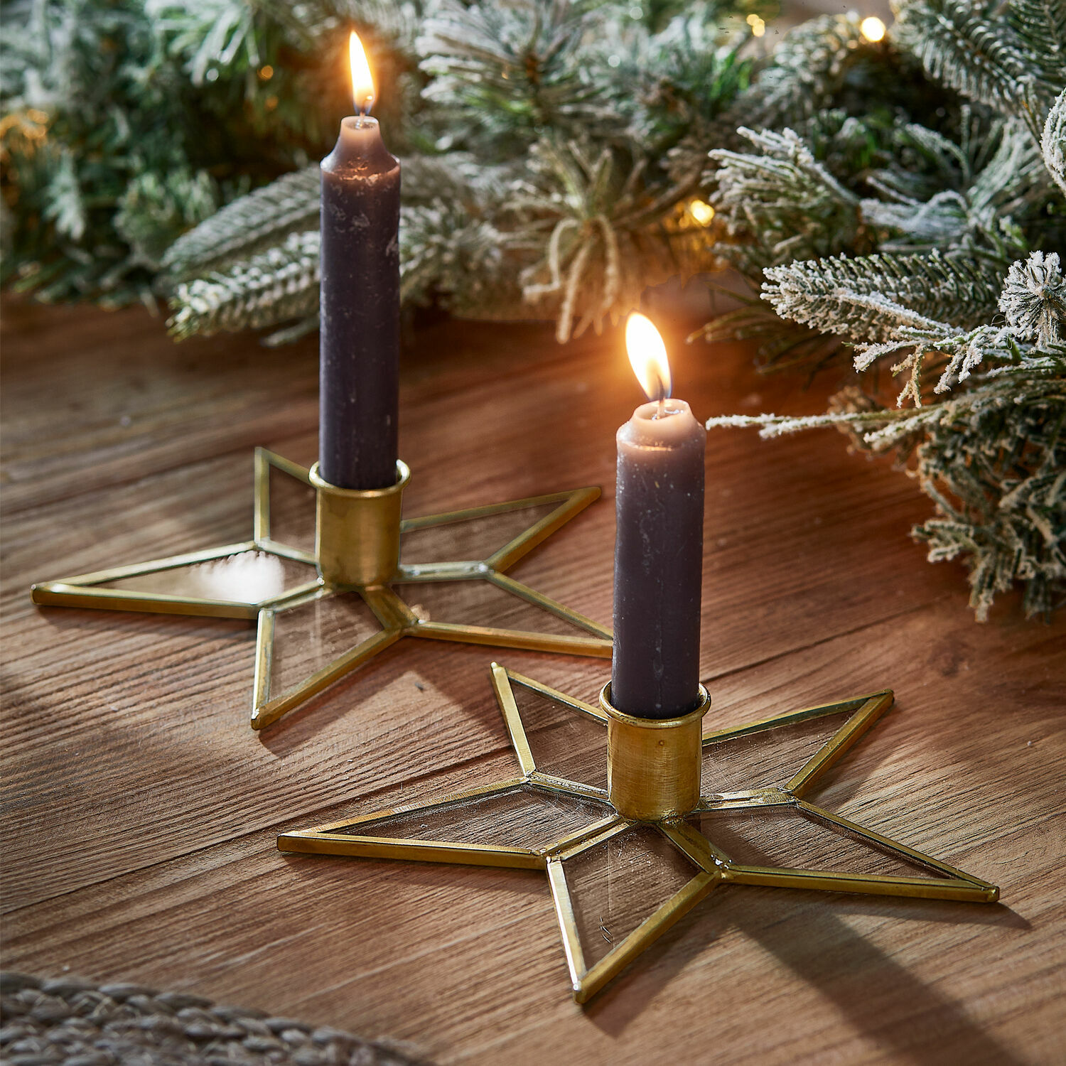 Coppia di portacandele Zaydan Set di due portacandele a forma di stella in vetro e metallo dorato con candele viola su tavolo in legno