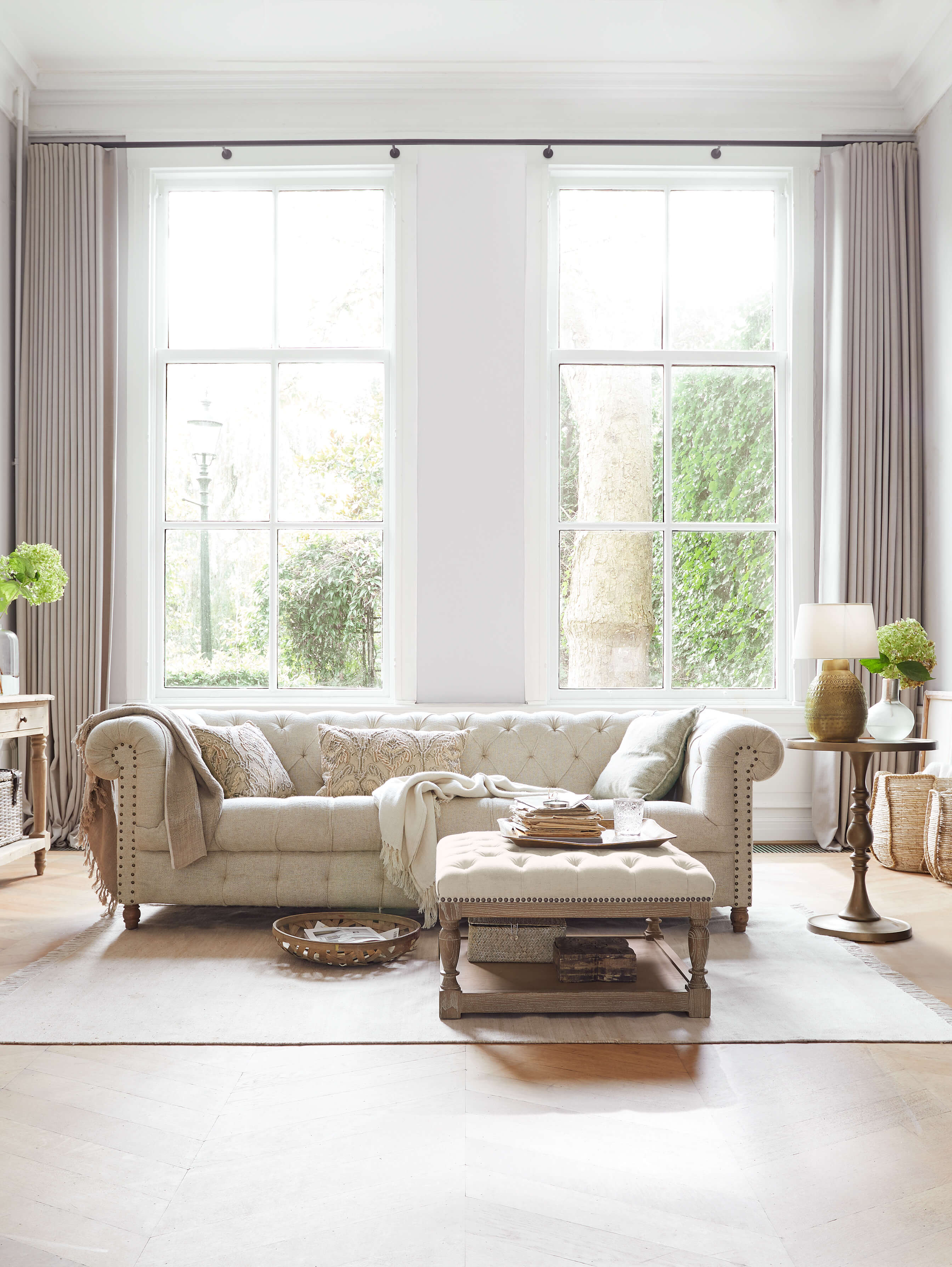 Divano Chesterfield beige trapuntato in tessuto in soggiorno luminoso con luce naturale