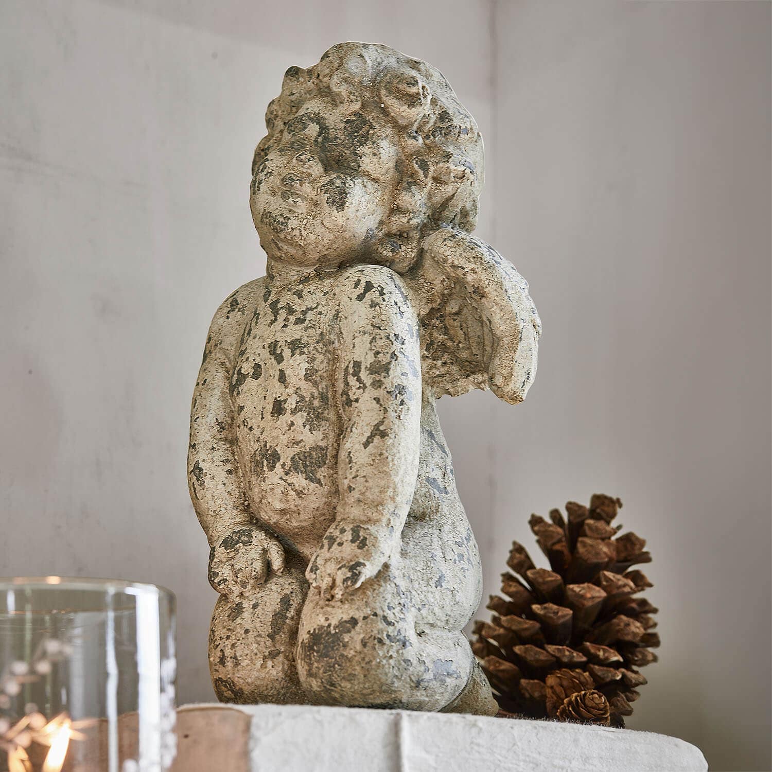 Statua di angelo in pietra invecchiata beige, decorazione d'interni con pigna naturale