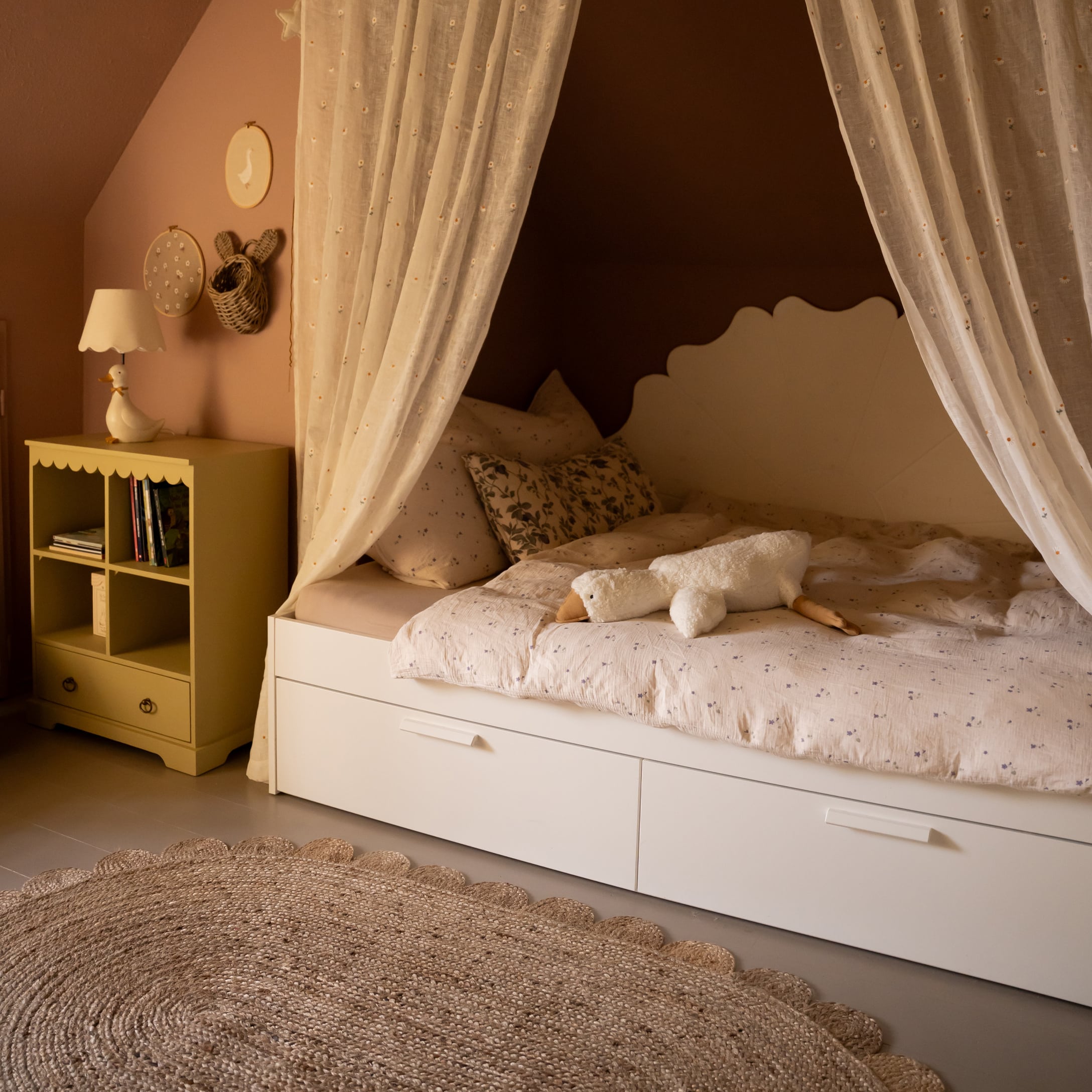 Letto per bambini bianco con tende leggere e peluche d'oca su copripiumino a fiori