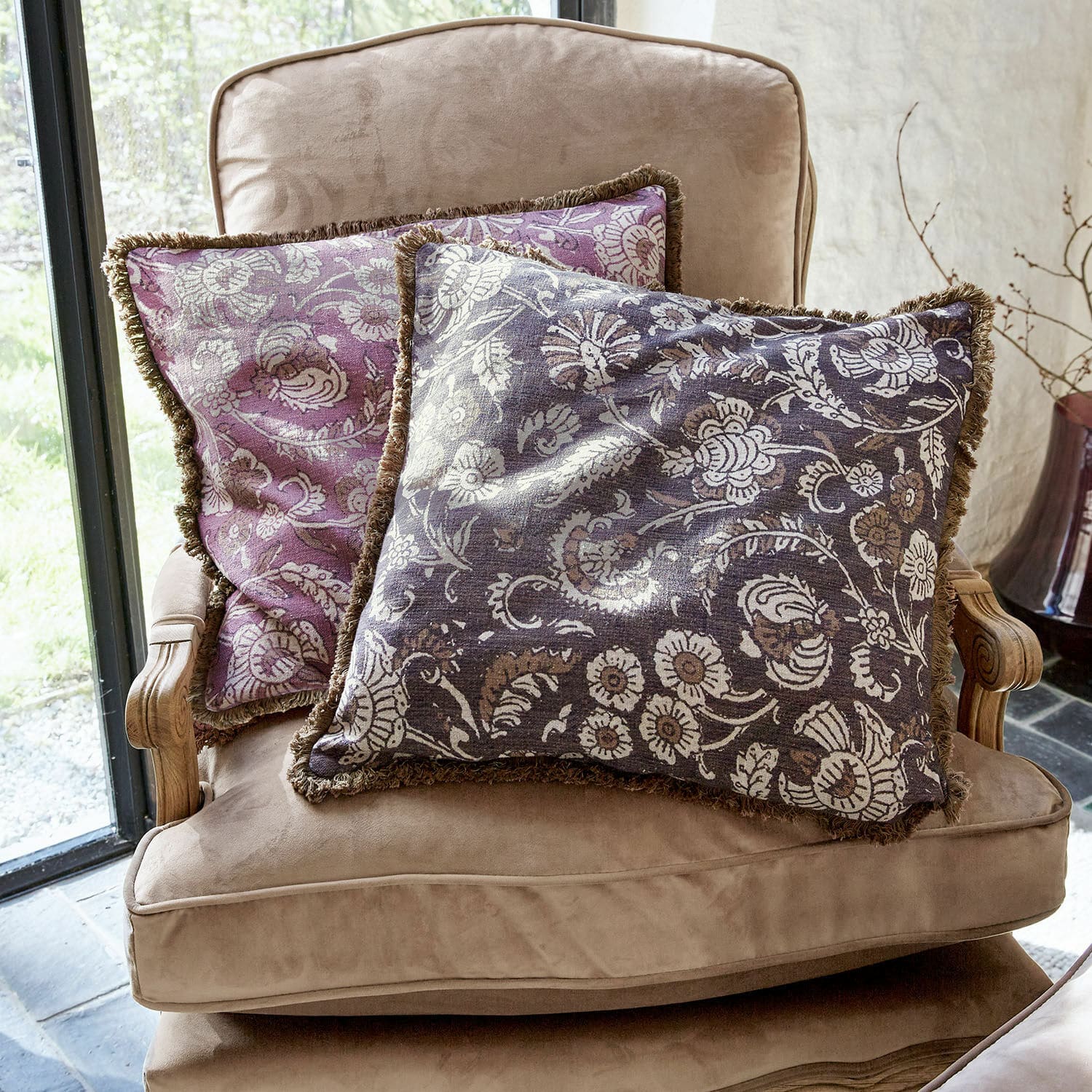 Coppia di copricuscini Lalluga Due cuscini decorativi con motivo floreale viola e grigio su una poltrona beige