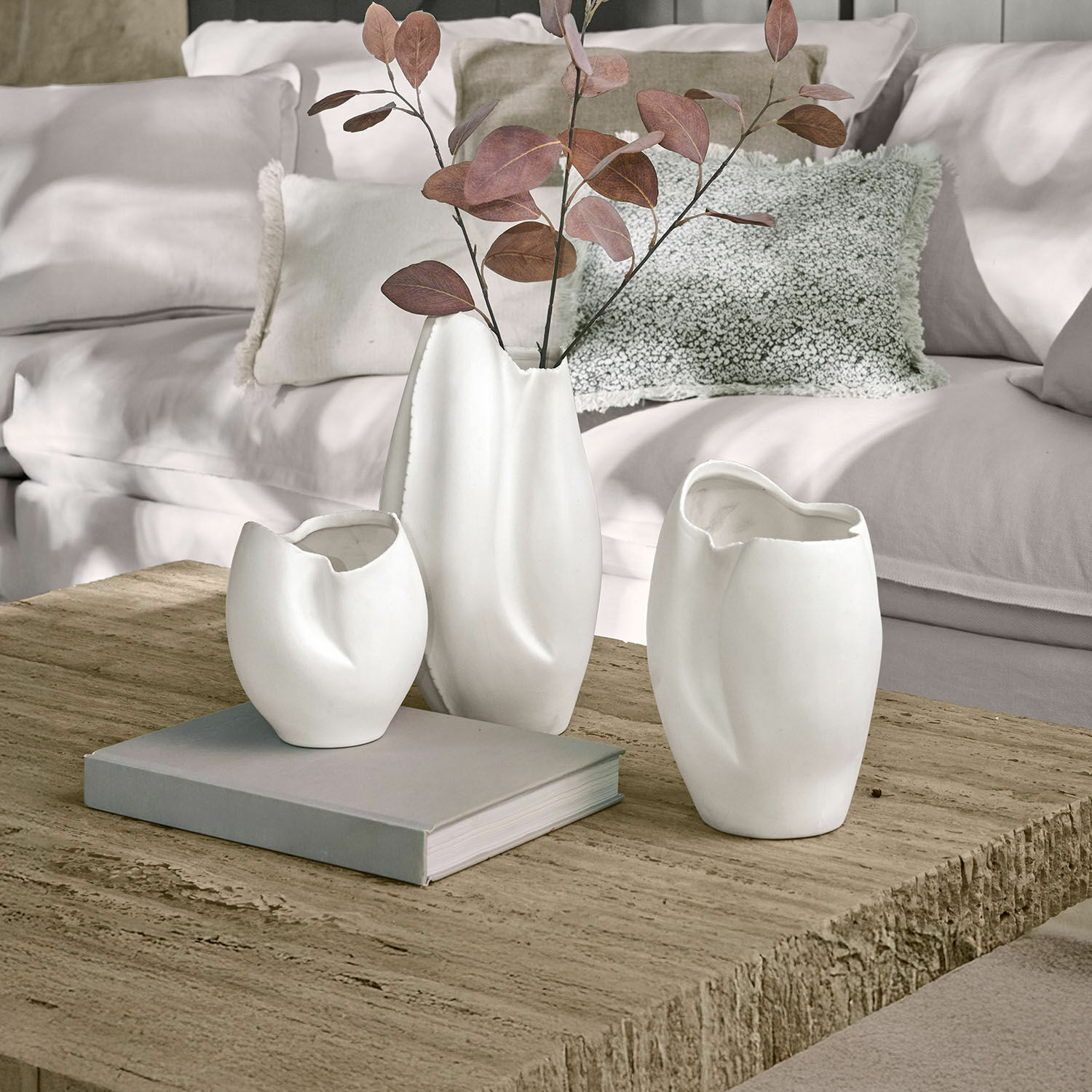 Set di 3 vasi Kazimad Set di tre vasi in ceramica bianca con forme irregolari su tavolo in legno in soggiorno