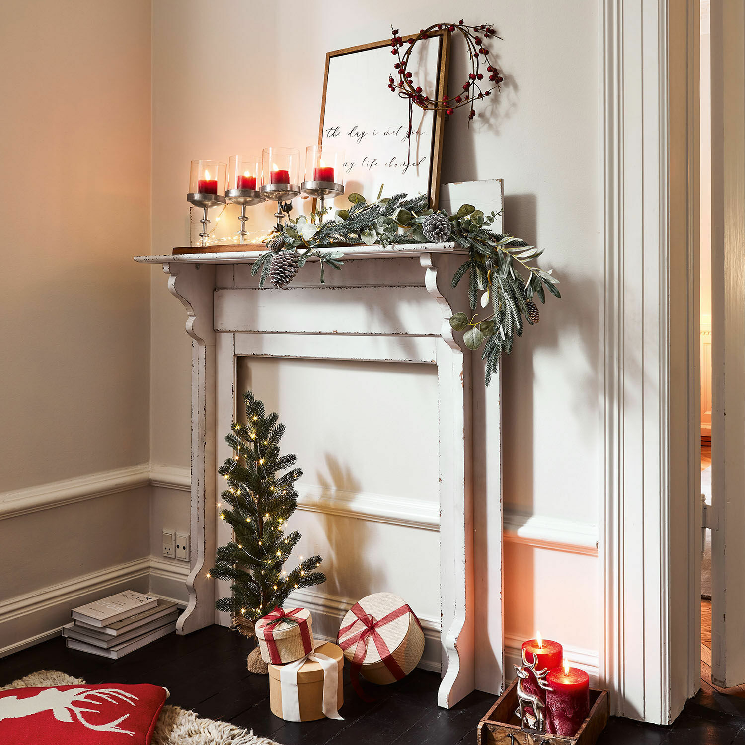 Consolle caminetto Cessieu Camino decorativo bianco in legno con ghirlanda verde, candele rosse e regali di Natale