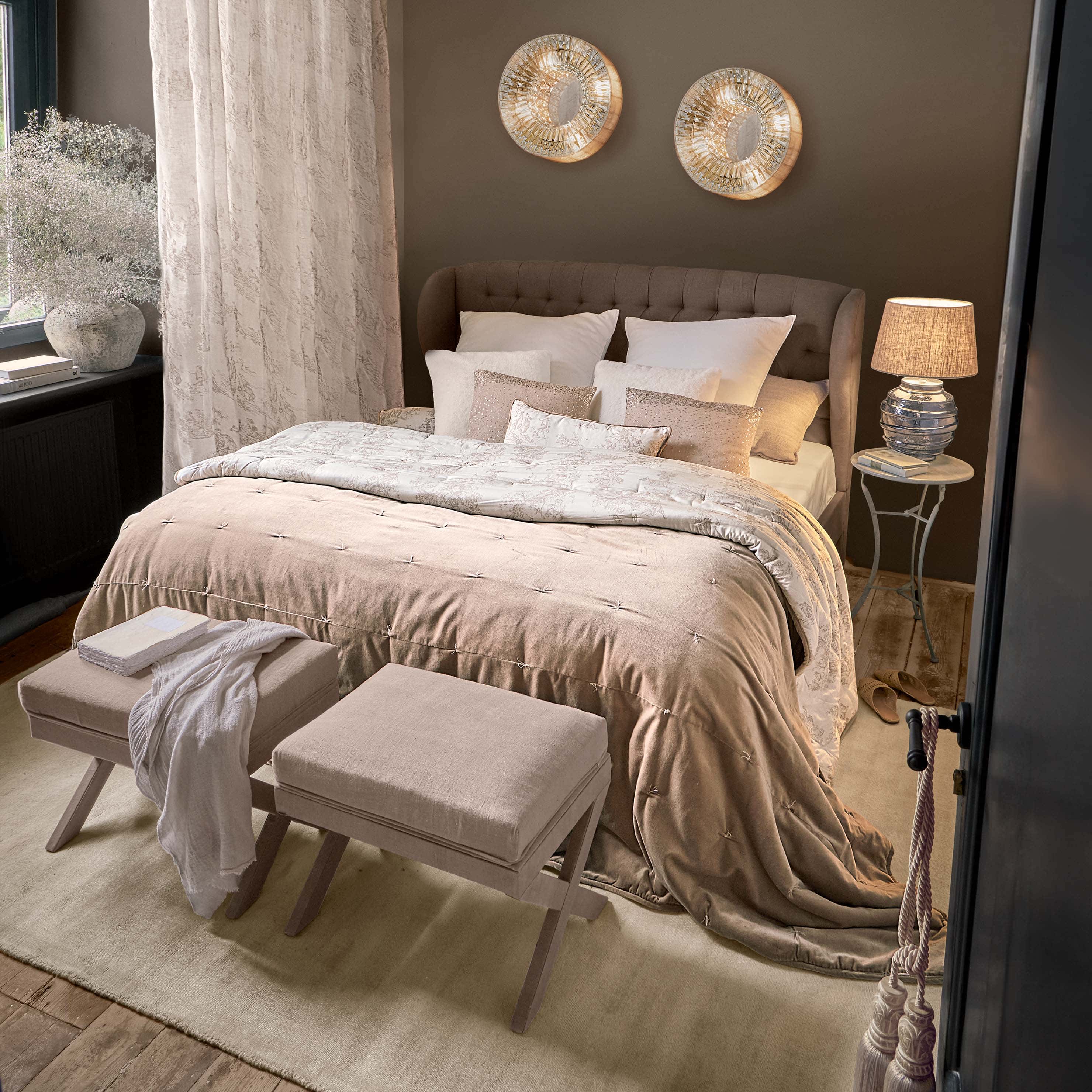 Camera da letto accogliente con letto imbottito marrone e biancheria beige con cuscini decorativi