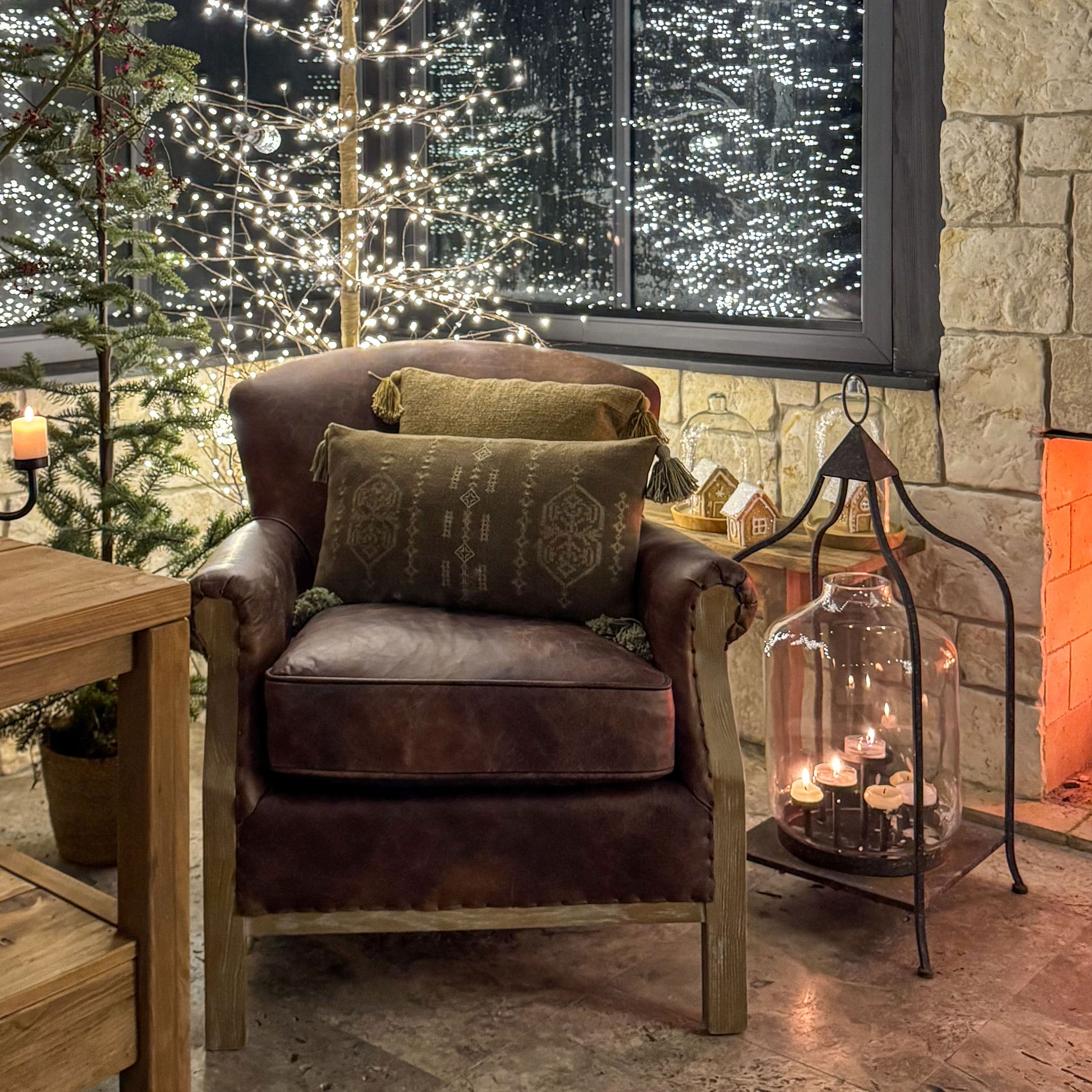 Poltrona in pelle marrone con cuscini verdi in ambiente accogliente con decorazioni natalizie e candele