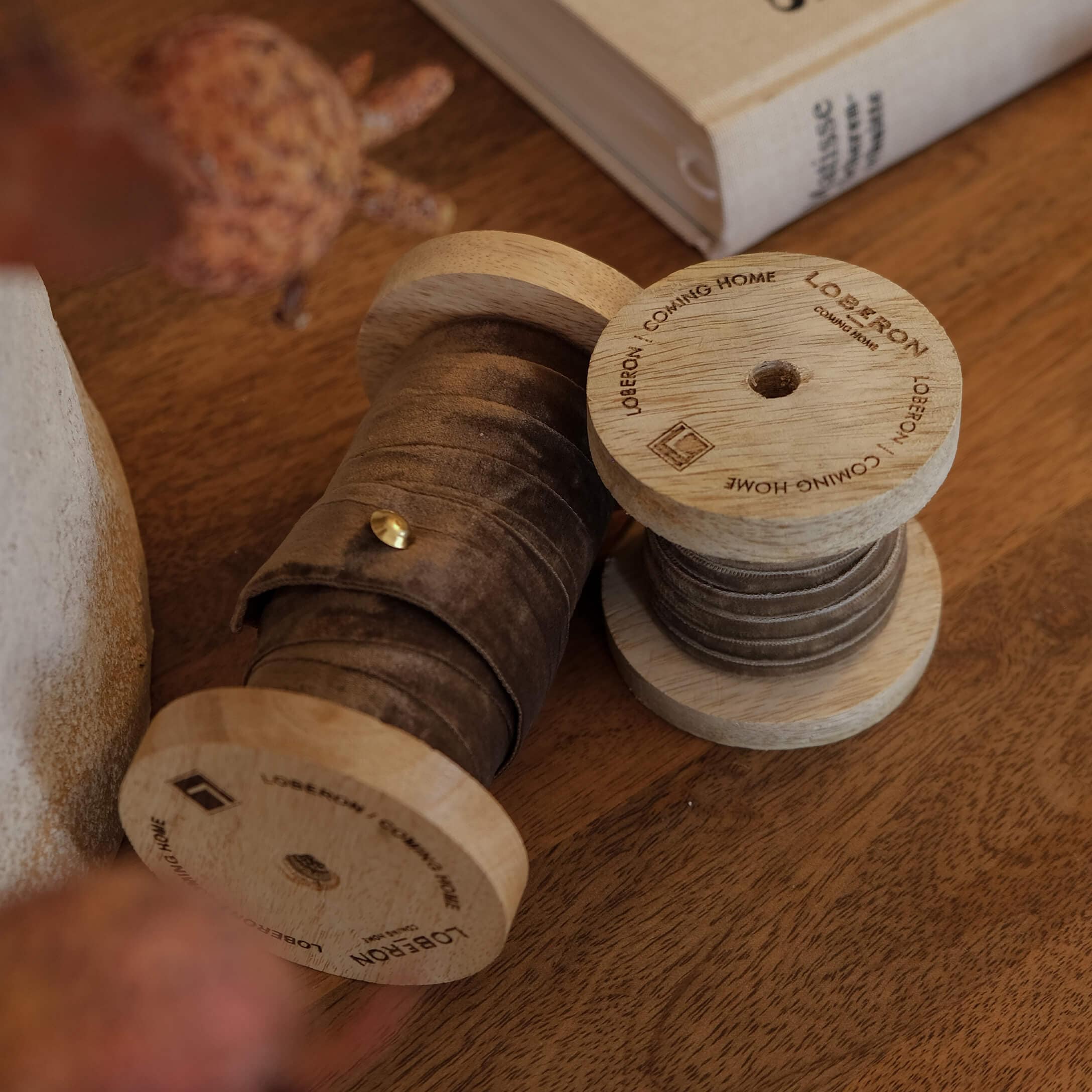 Bobine in legno con nastro di velluto marrone su tavolo in legno, decorazione d'interni