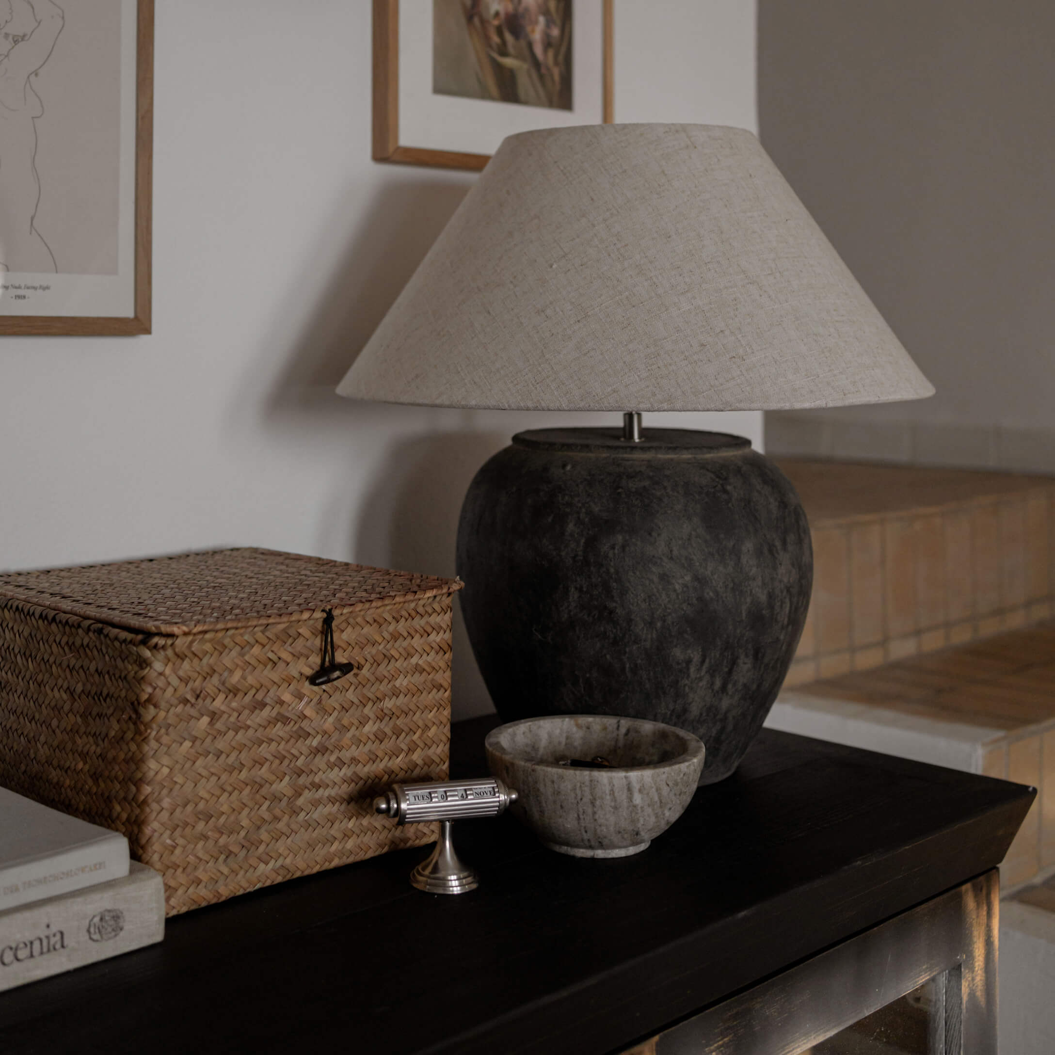 Lampada da tavolo con base in ceramica nera e paralume beige su tavolo scuro in soggiorno