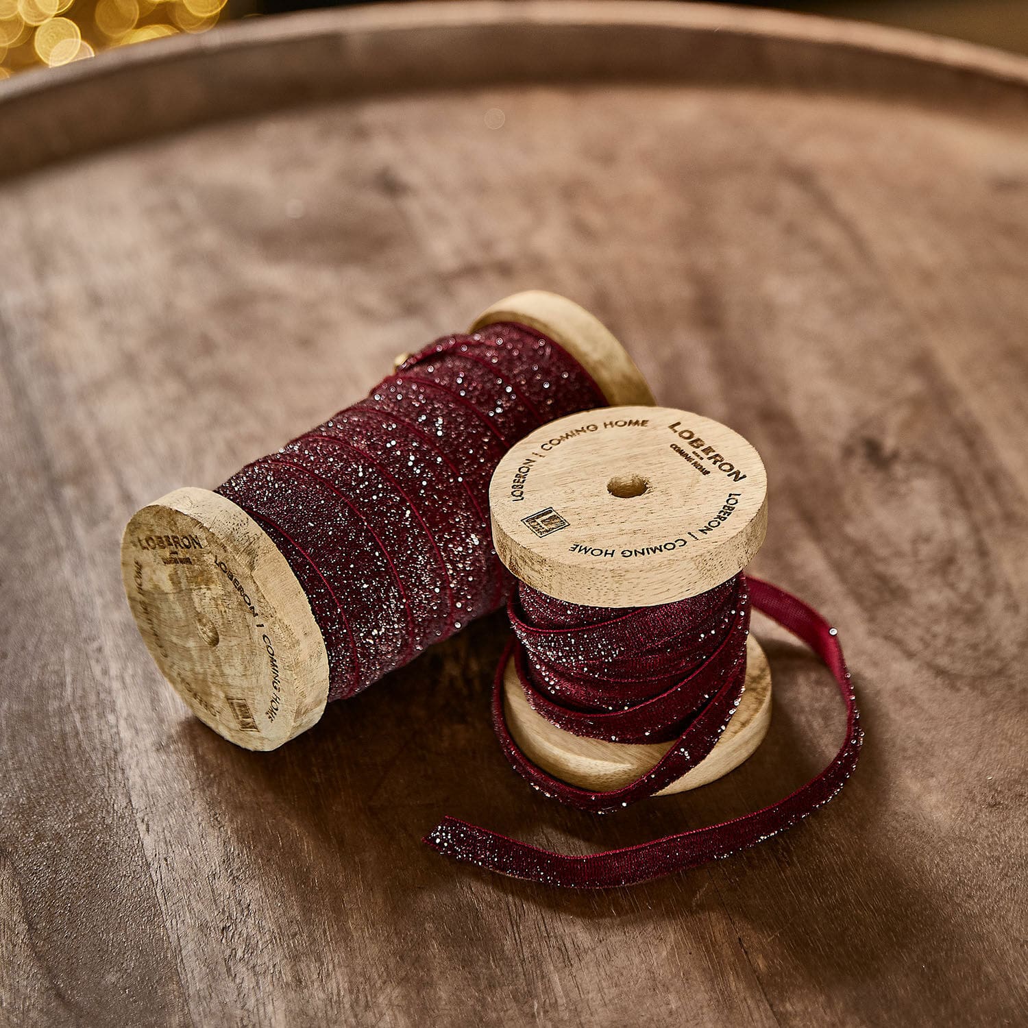 Coppia di nastri di velluto Risorio Nastro bordeaux glitterato su bobine di legno su tavolo in legno per decorazioni e fai-da-te
